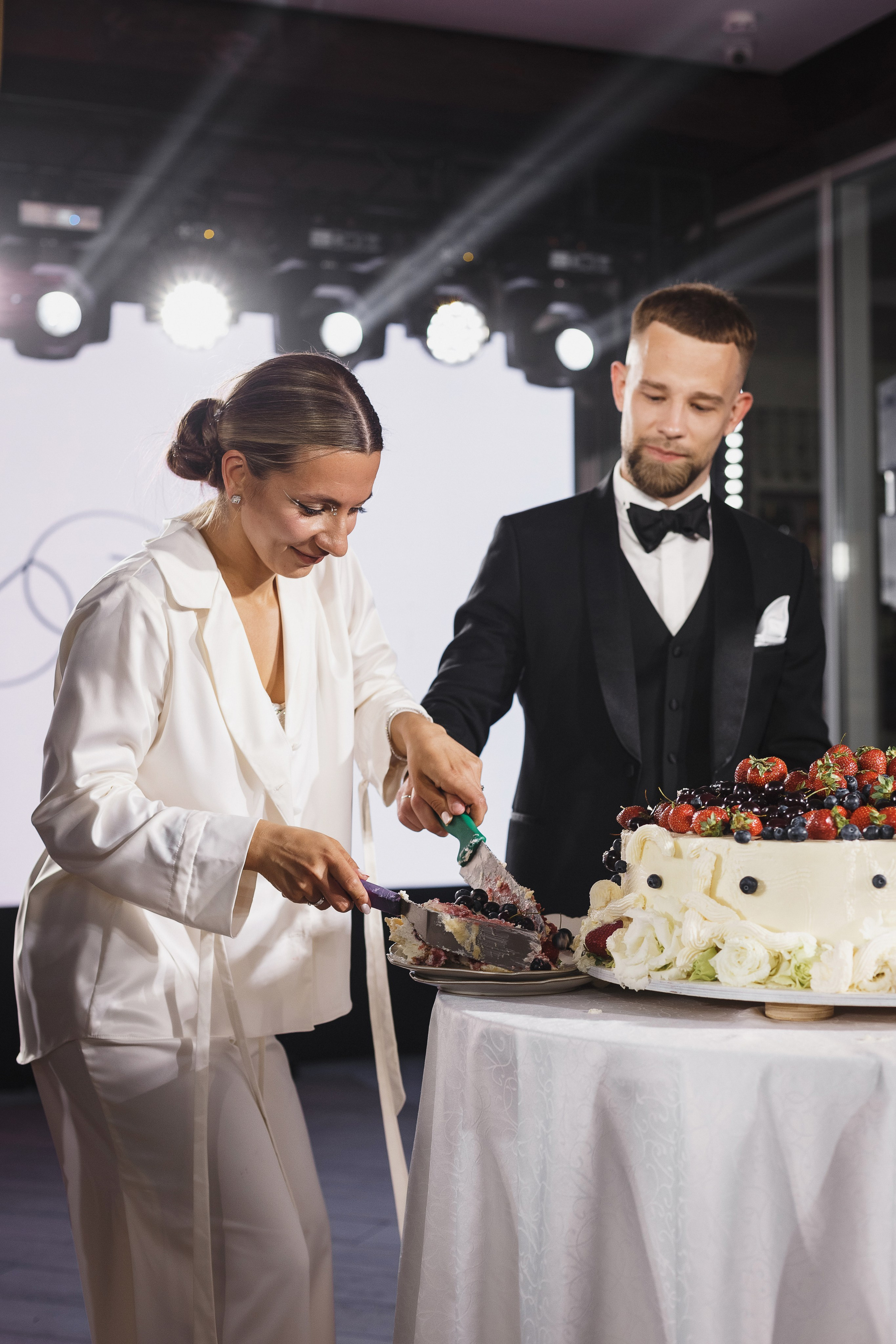 Жених и невеста разрезают свадебный торт с ягодами на банкете в Golden Horse, свадебный фотограф Таганрог