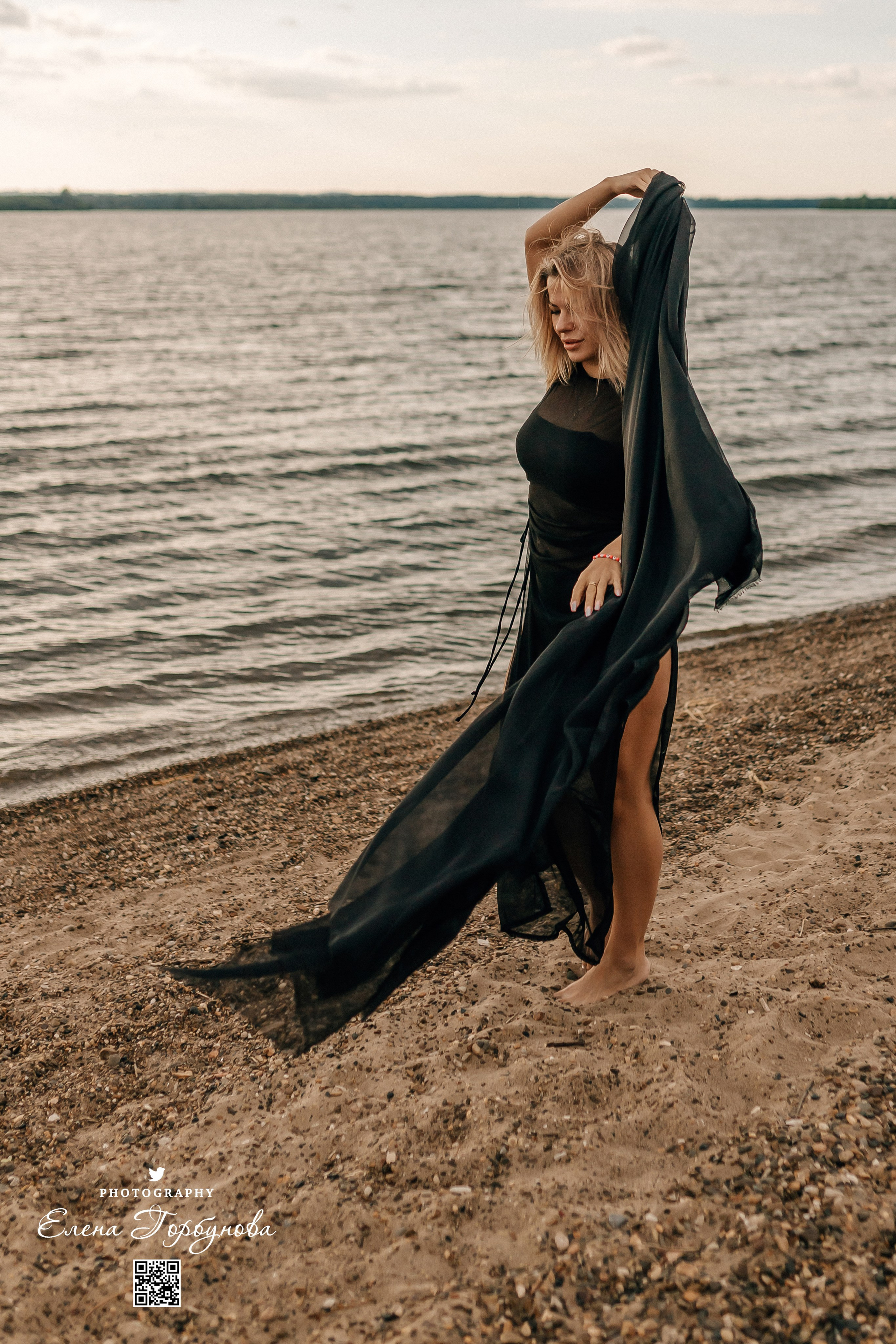 Фотосессия с черной тканью. Легкая черная вуаль летит на вертру. Фотосессия у реки черная серия с тканью. Девушка укуталась в черную ткань. Прогулка по набережной. Песок, речка, модель в черном. Качели над водой, Закат. Девушка лежит на песке. В зеленых деревьях