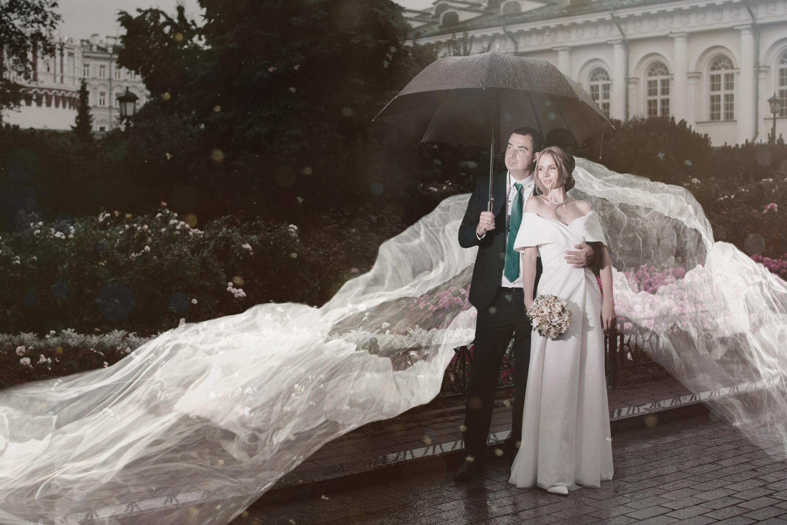 красивая свадебная фотосьемка рядом с Кремлём в Москве на улице где невеста стоит с женихом и идет дождь 