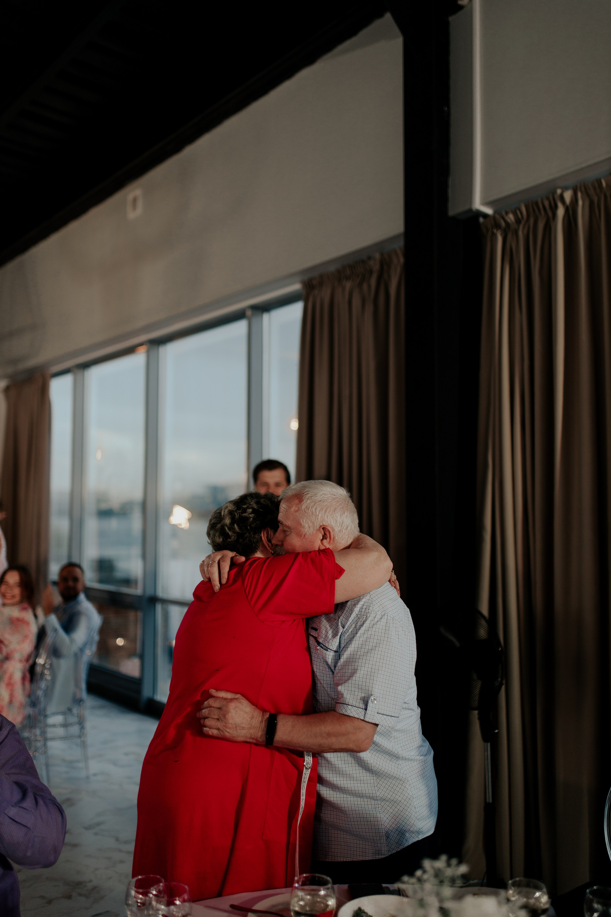 Бабушка и дедушка невесты обнимаются вечером на банкете — нежный взгляд