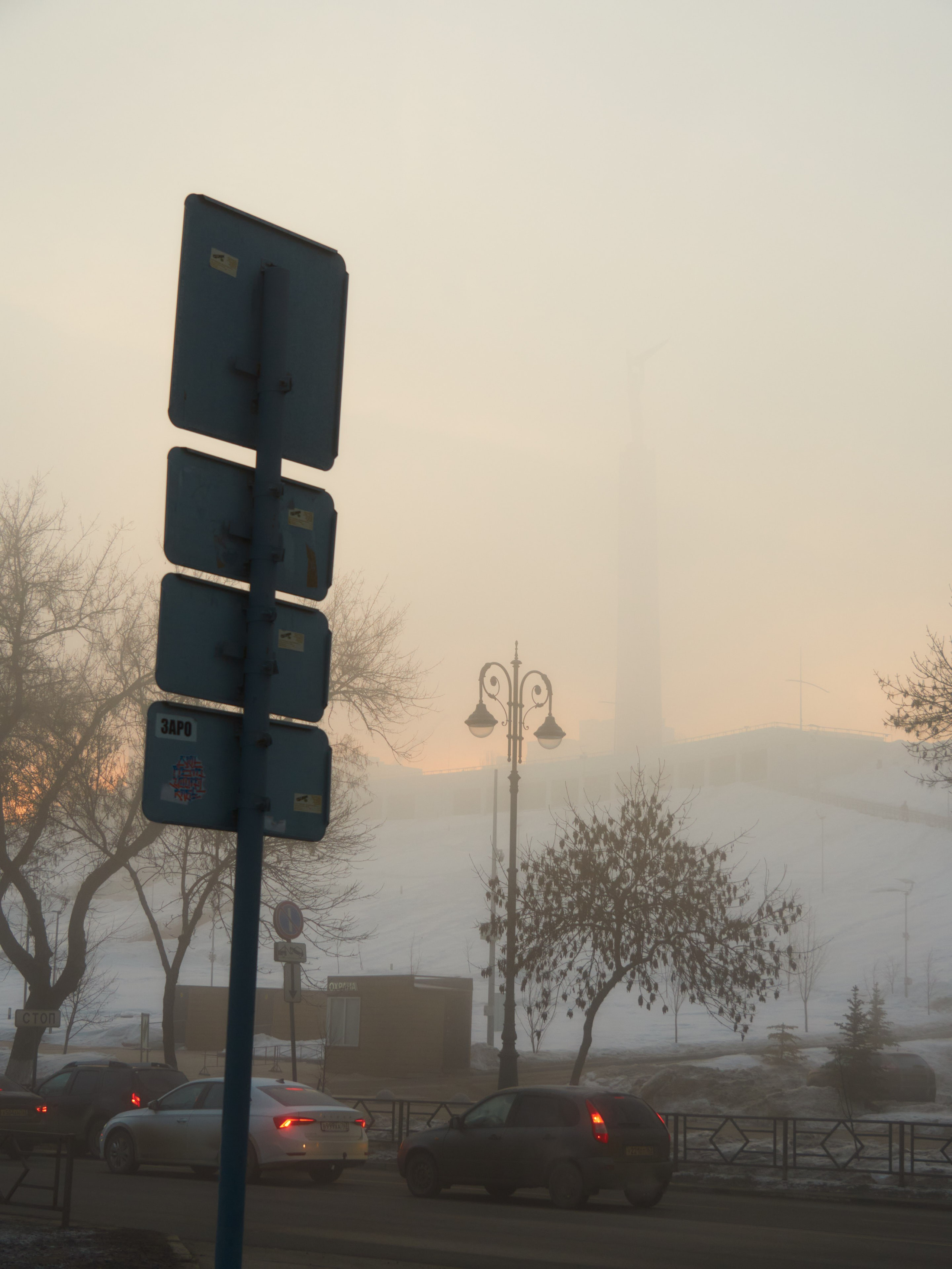 Дорожный знак едва виден в тумане, усиливая ощущение неизвестности впереди