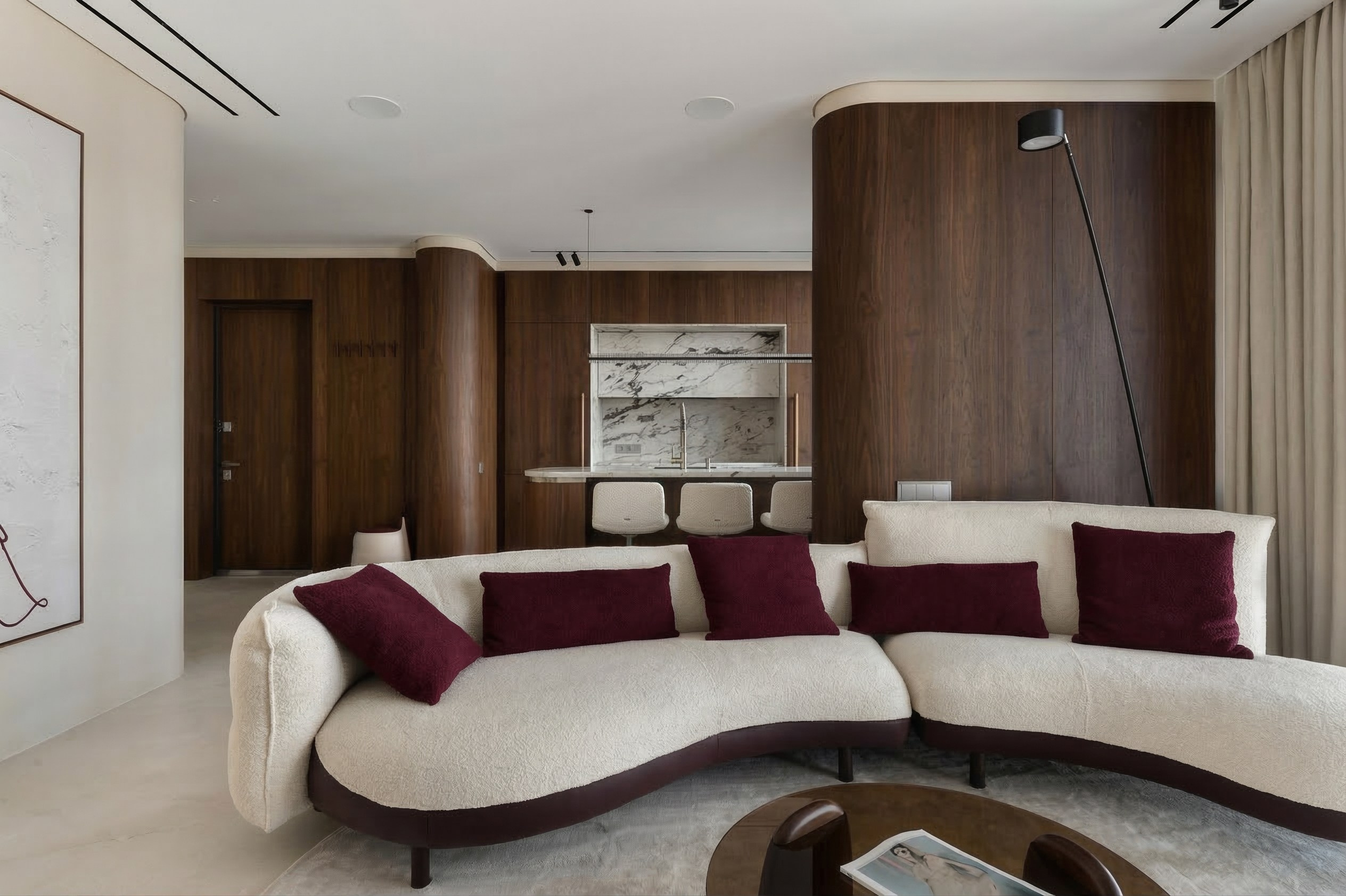 Интерьер гостиной в ЖК ONYX Deluxe: белый радиусный диван с вишневыми подушками, большое минималистичное панно на стене и стены в темном шпоне. Дизайн Валерии Котович.