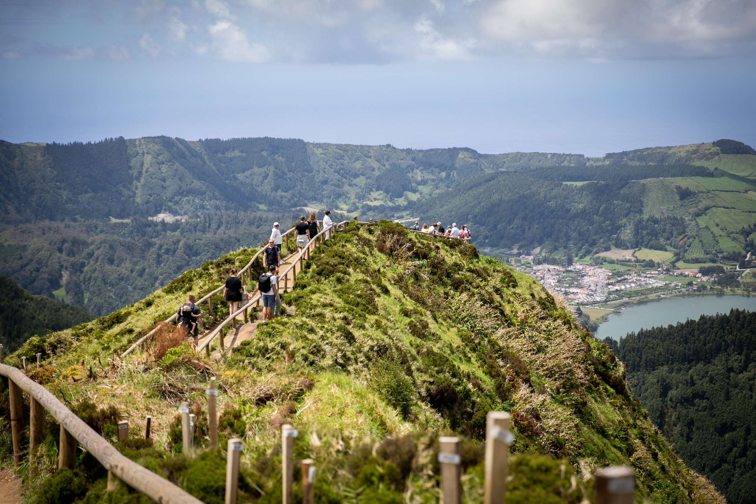 Young women exploring the breathtaking scenery of the Azores, with rolling hills, the ocean, and sky as their backdrop