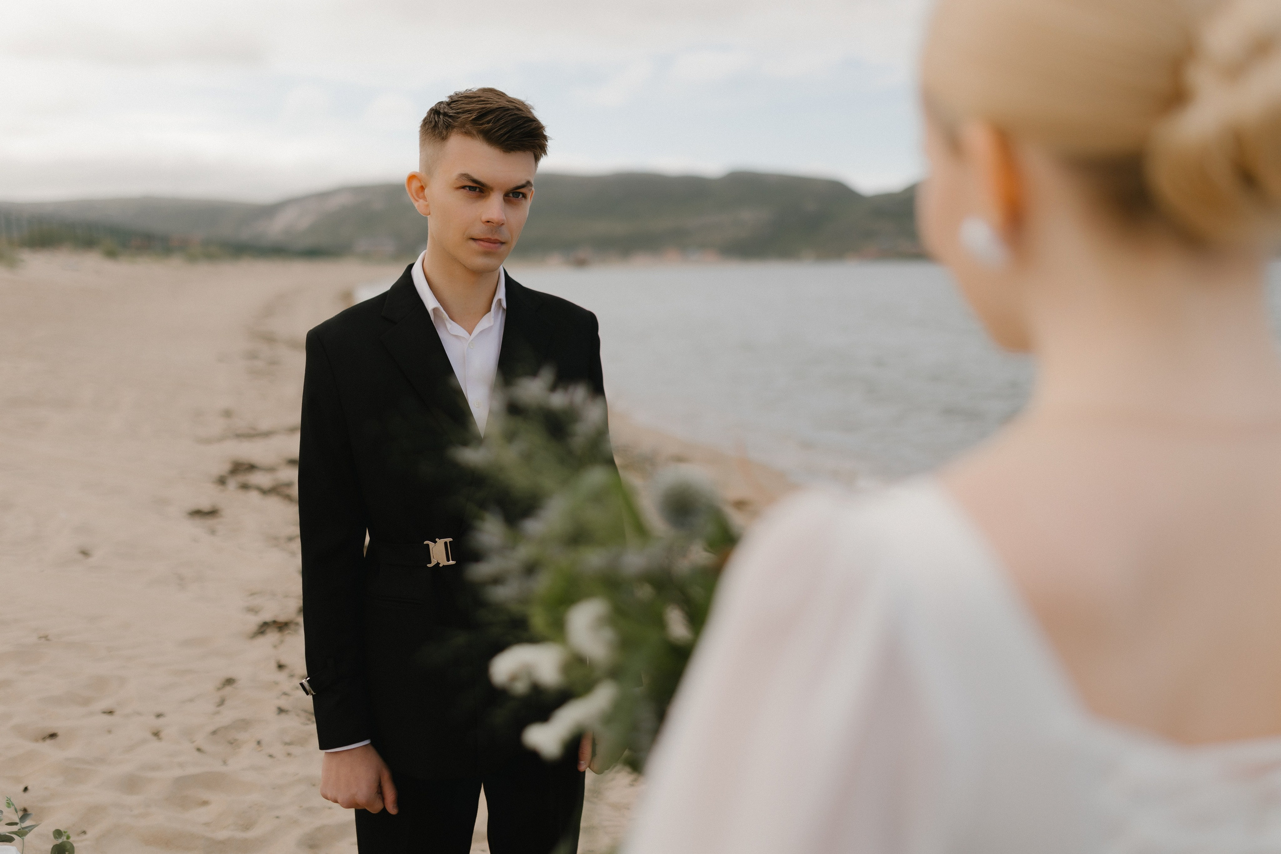 Нежный взгляд жениха на свою возлюбленную, стоящую перед ним на пляже.