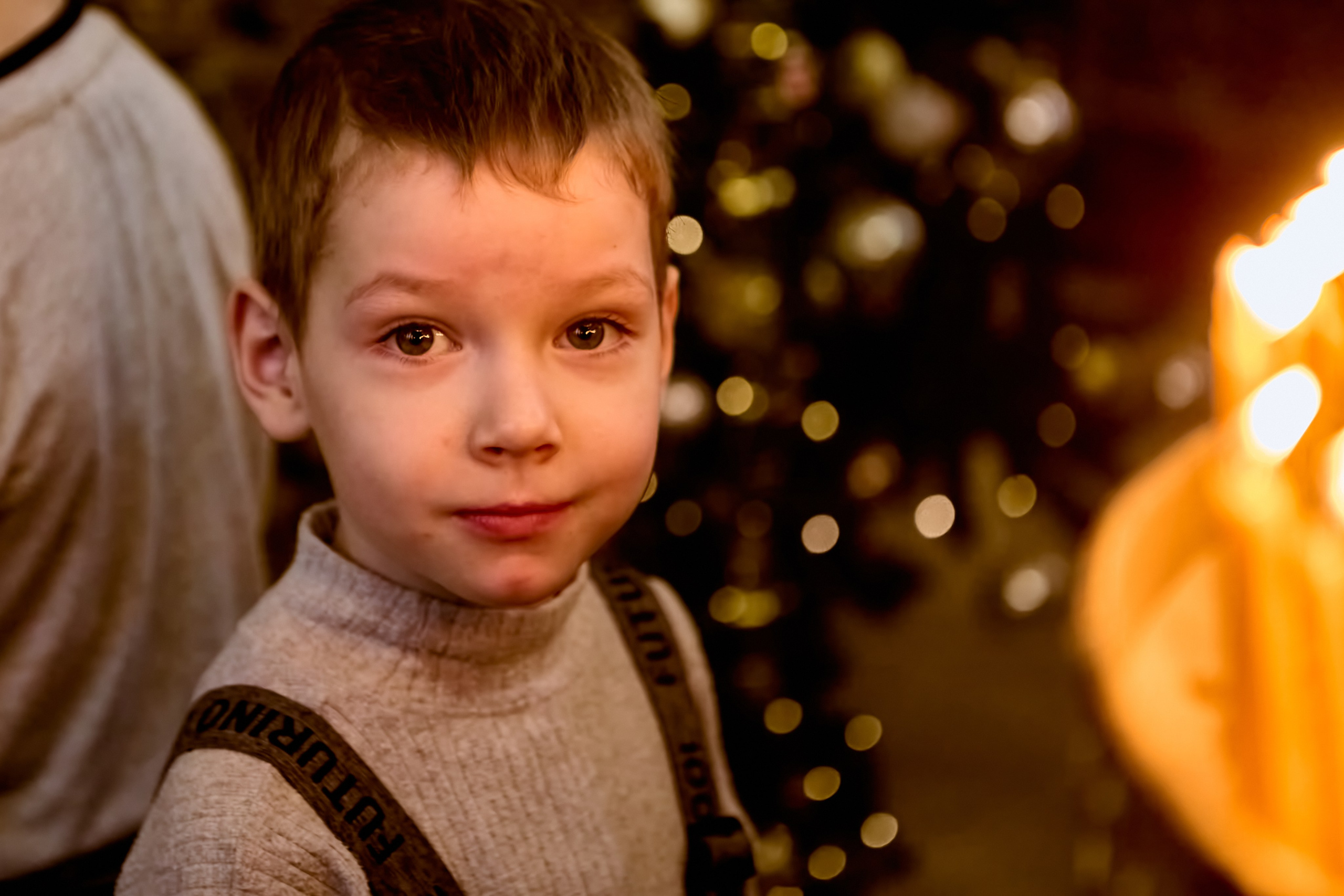 Малыш стоит перед подсвечником и смотрит на фотографа