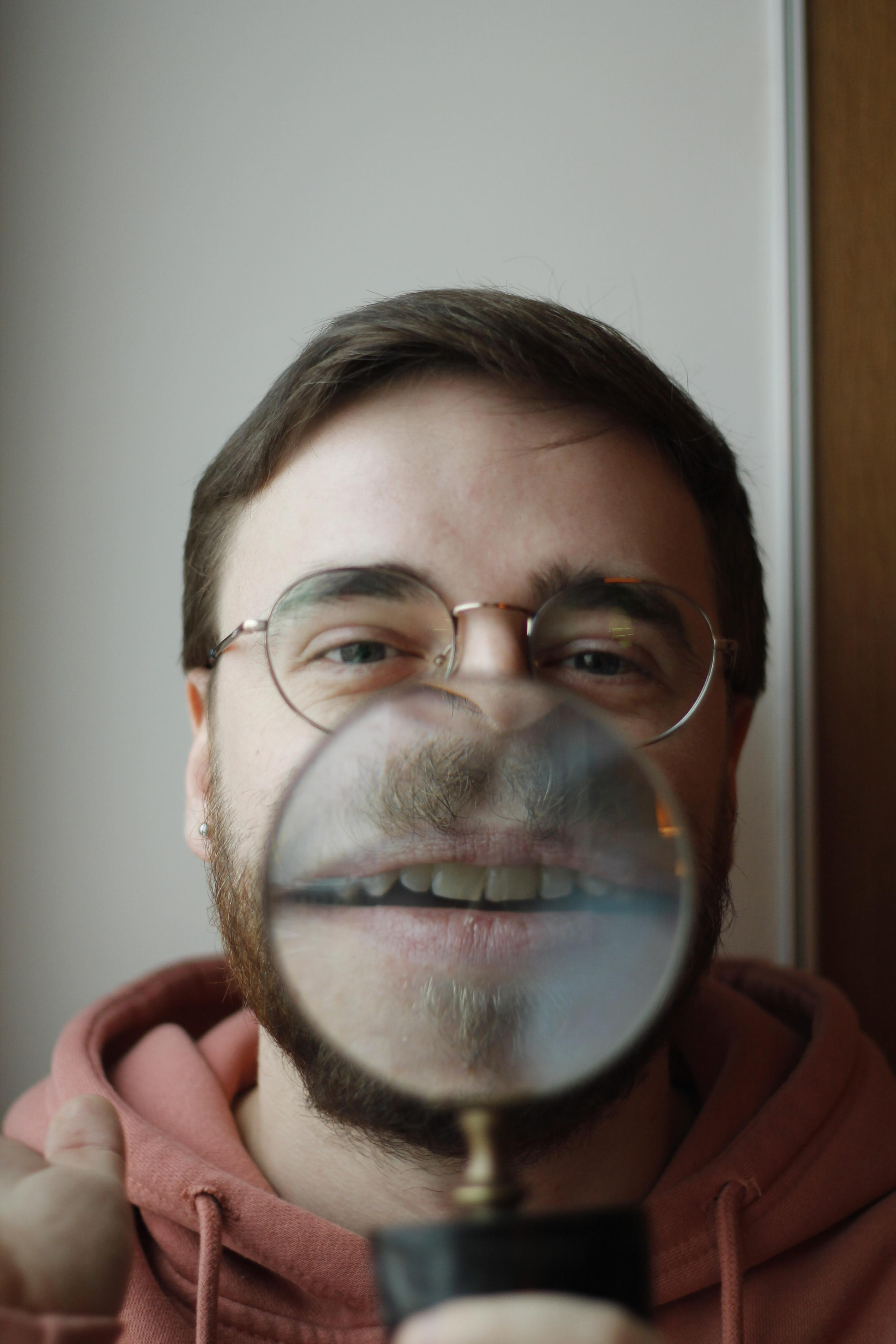 Portrait of a man with magnifier to enlarge his mouth