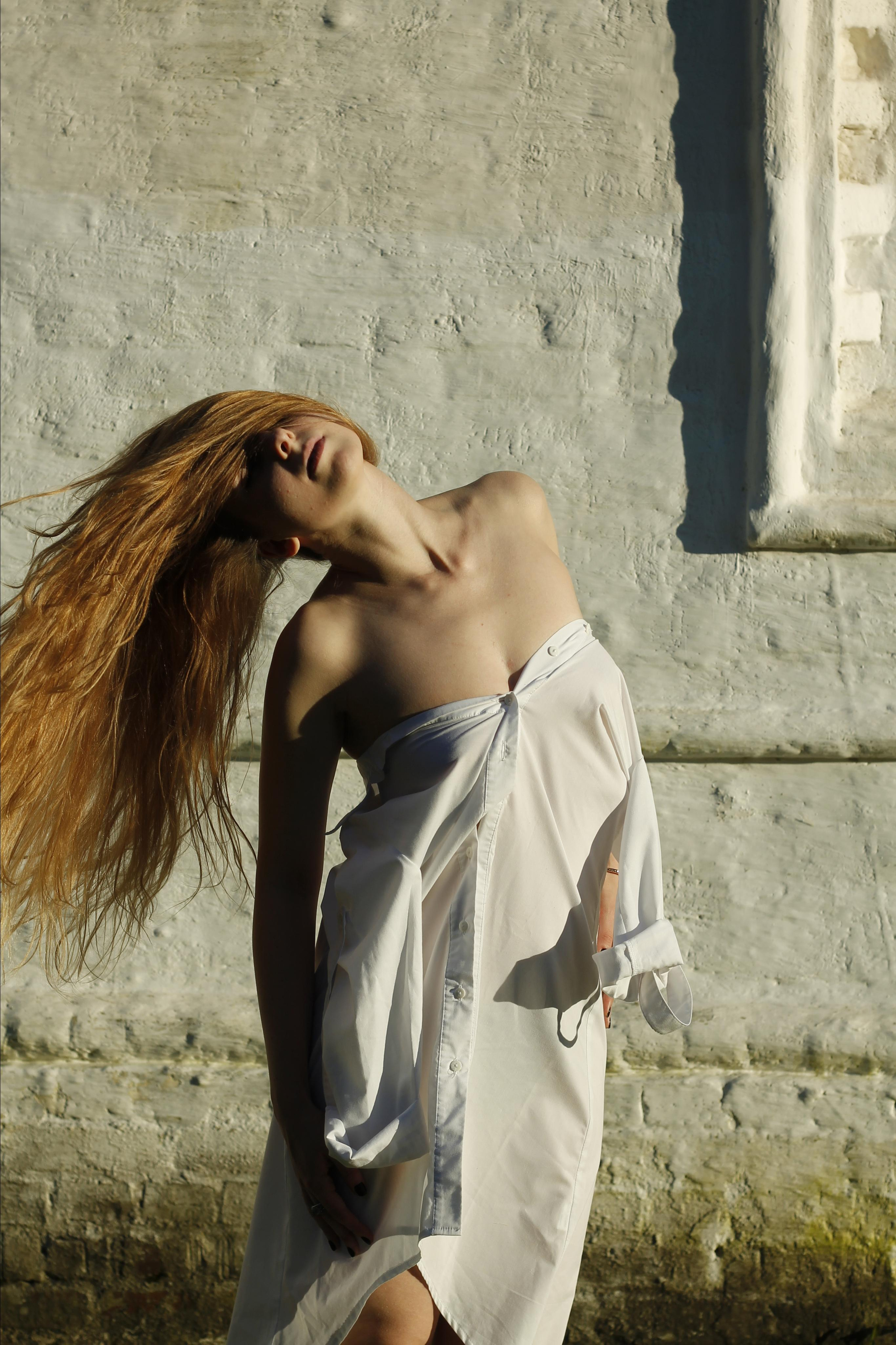 Woman in white shirt shaking her head on the white wall background
