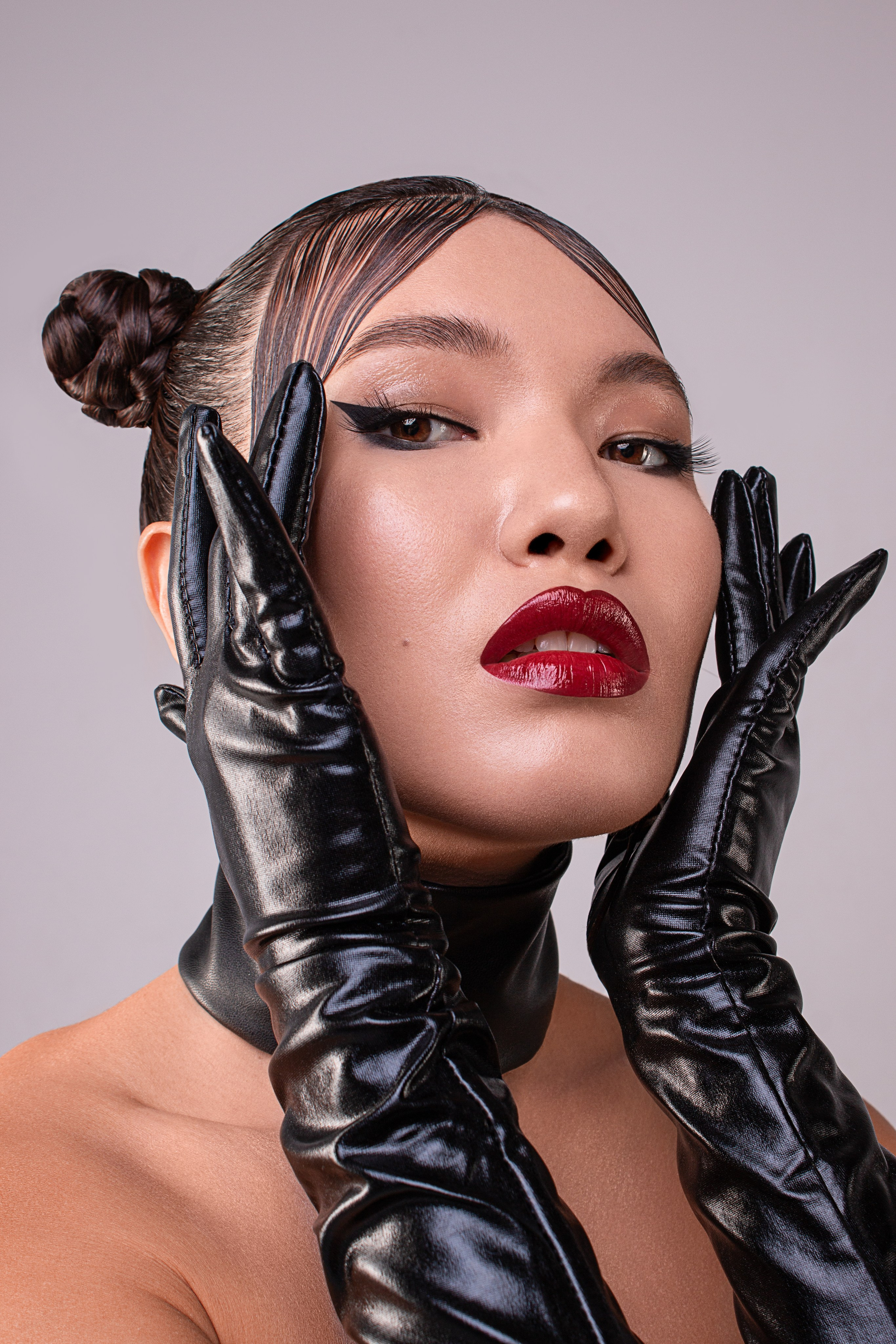 Портрет девушки модели азиатской внешности с ярким макияжем в черных кожаных перчатках