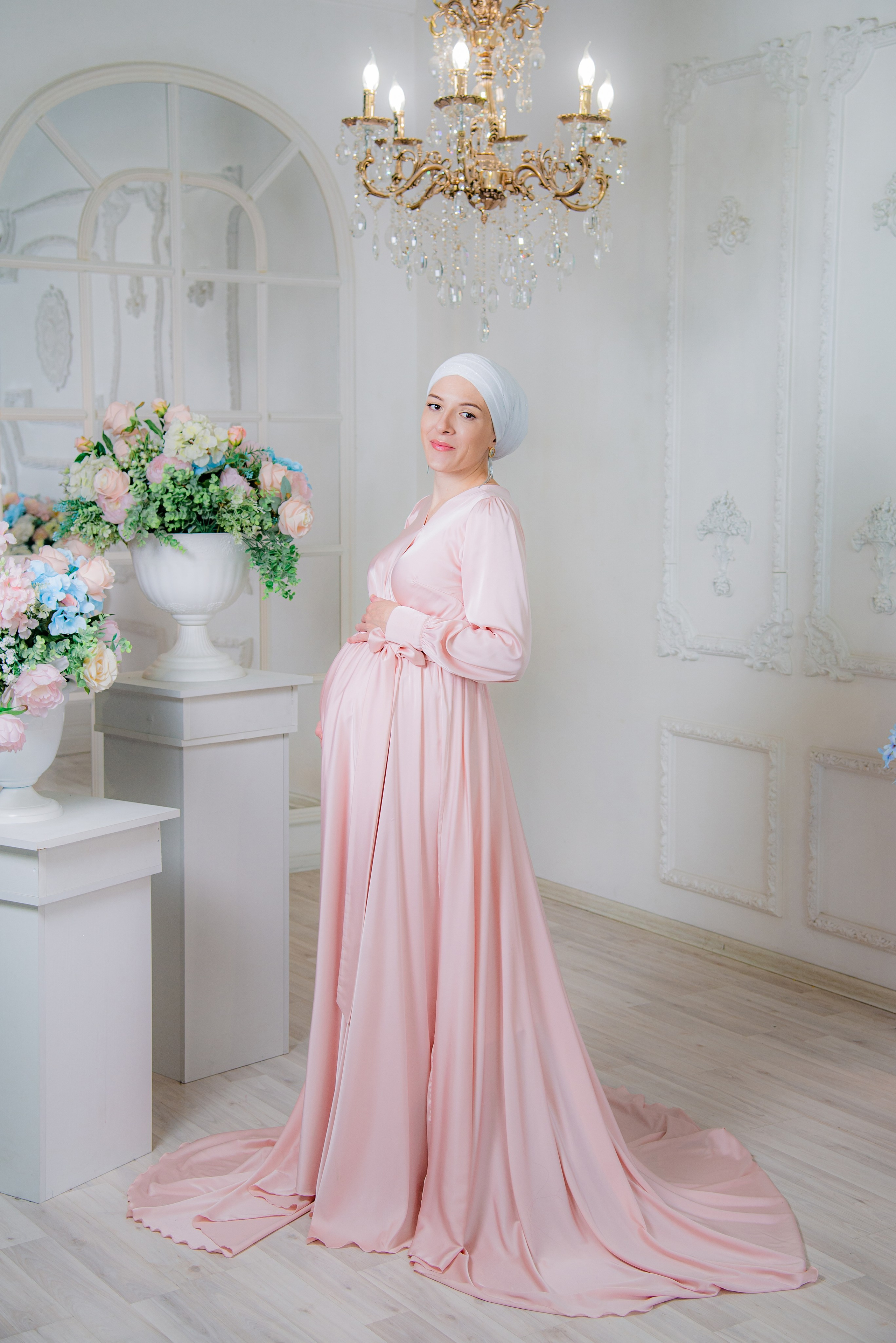 Фотосессия беременных в фотостудии в Уфе: будущая мама в элегантном платье из проката, с профессиональным макияжем и прической. Она счастливо позирует на фоне стильного интерьера, отражая красоту и нежность материнства.