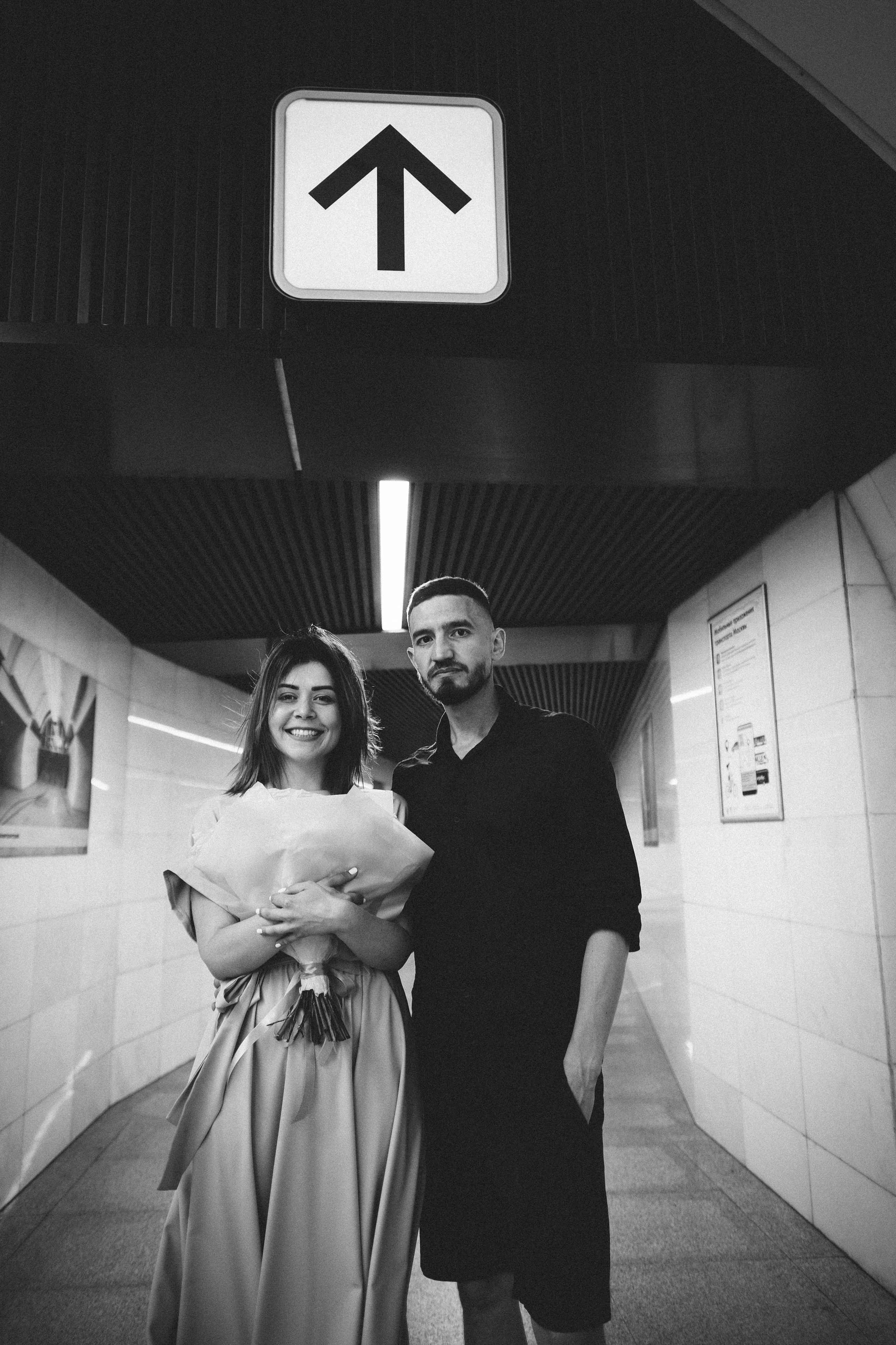 Пара в метро Москвы, а над ними указывающая направление движения стрелка.