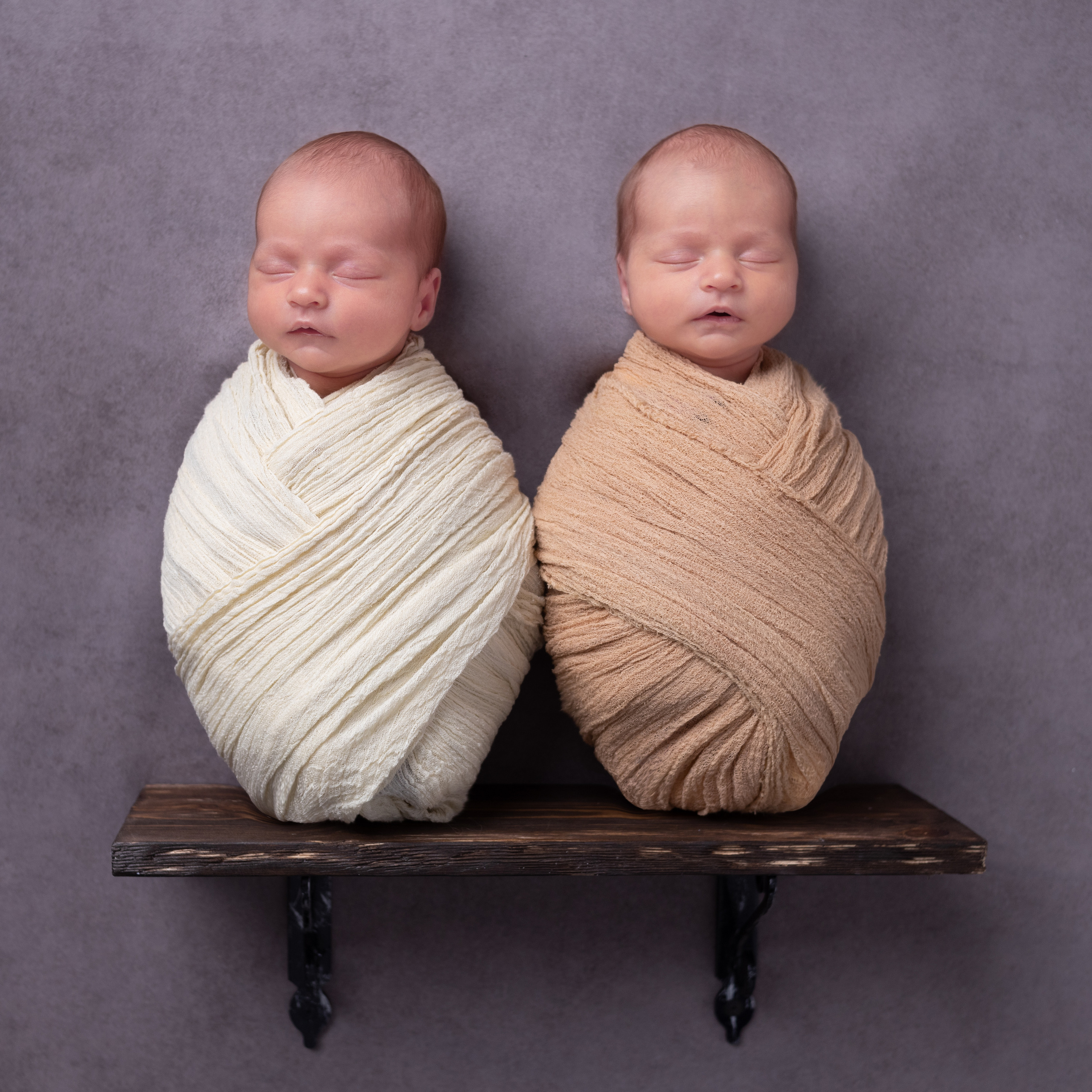 близнецы девочки позируют в коконах на книжной полке