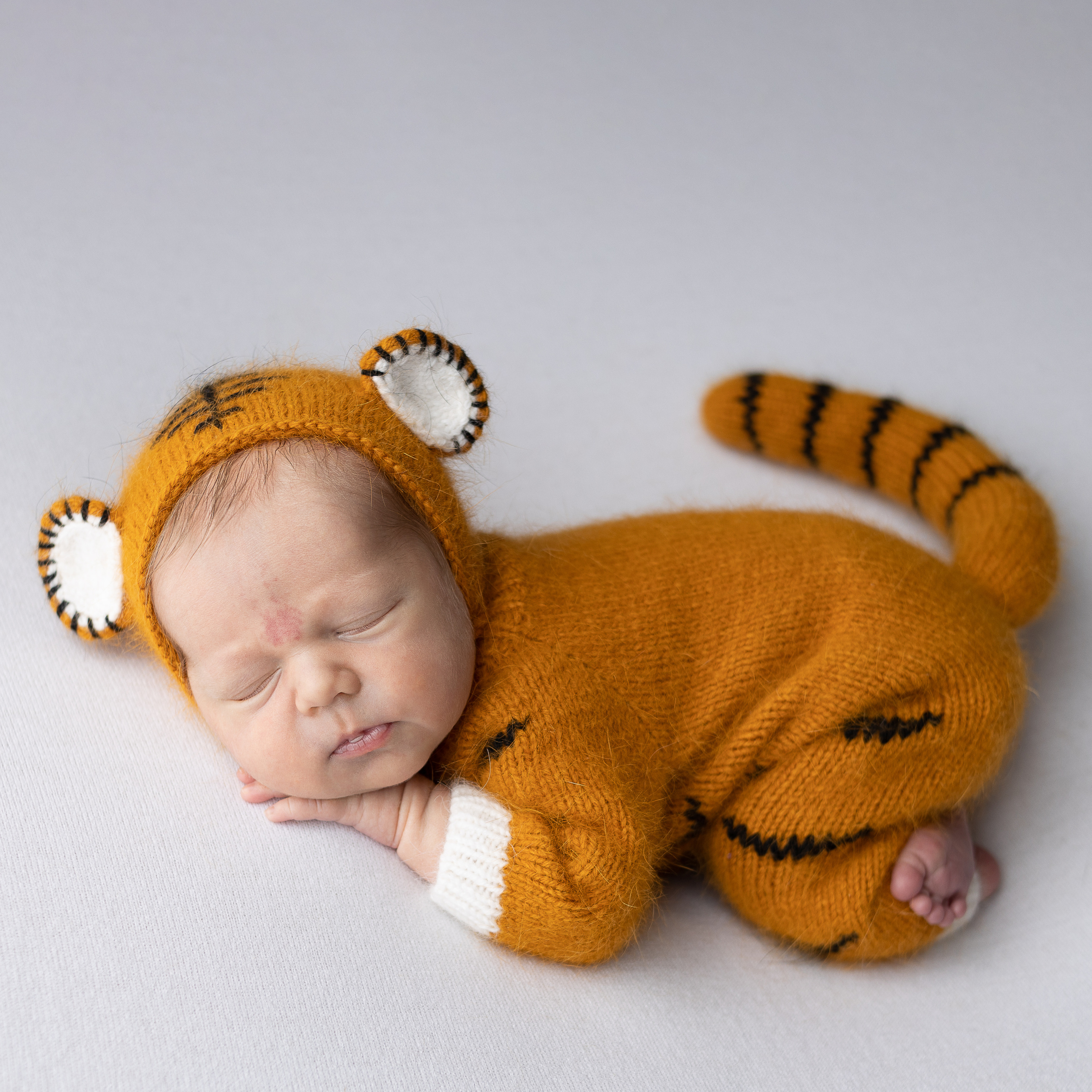 младенец лежит на животике в костюме тигренка