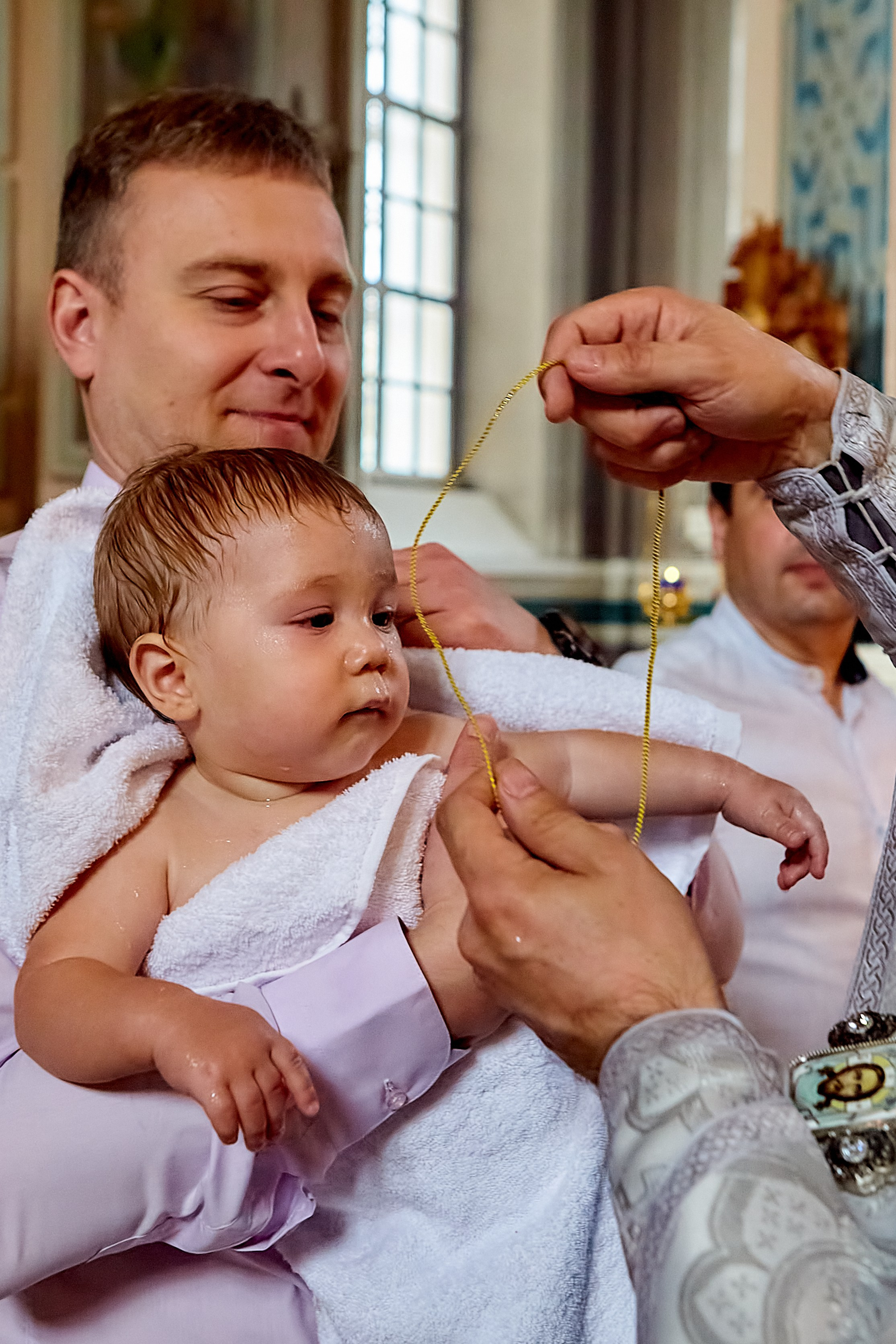 Батюшка священник одевает нательный крестик после купели