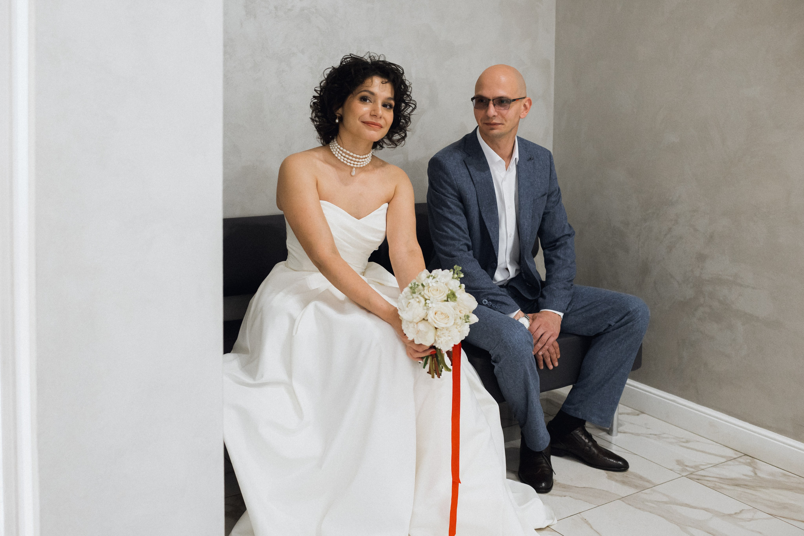 Эмоции перед свадьбой: жених и невеста в ожидании регистрации в Центральном ЗАГСе Архангельска сидят с букетом  улыбками  у кабинете регистрации 