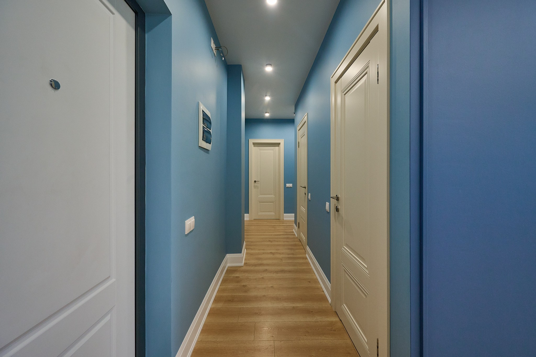 коридор голубые стены входная белая дверь светлый ламинат 