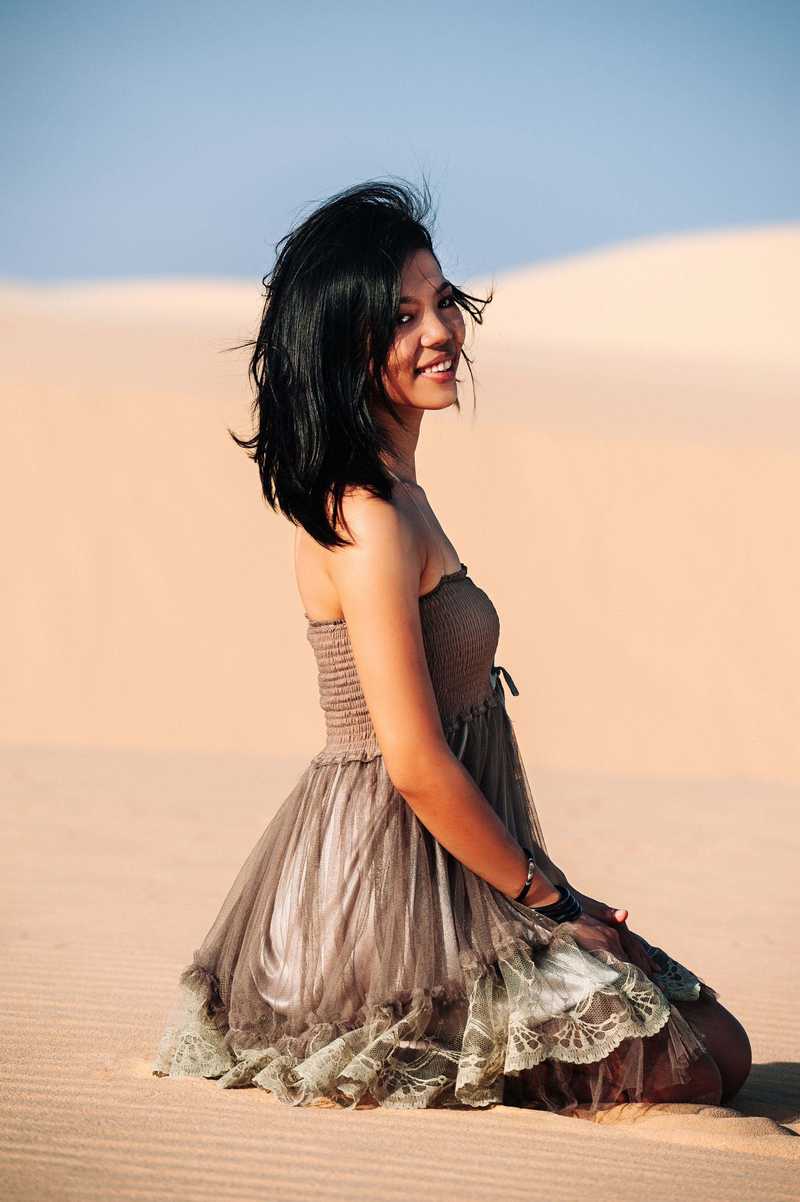 Молодая вьетнамская девушка сидит в платье в дюнах Муине, Вьетнам