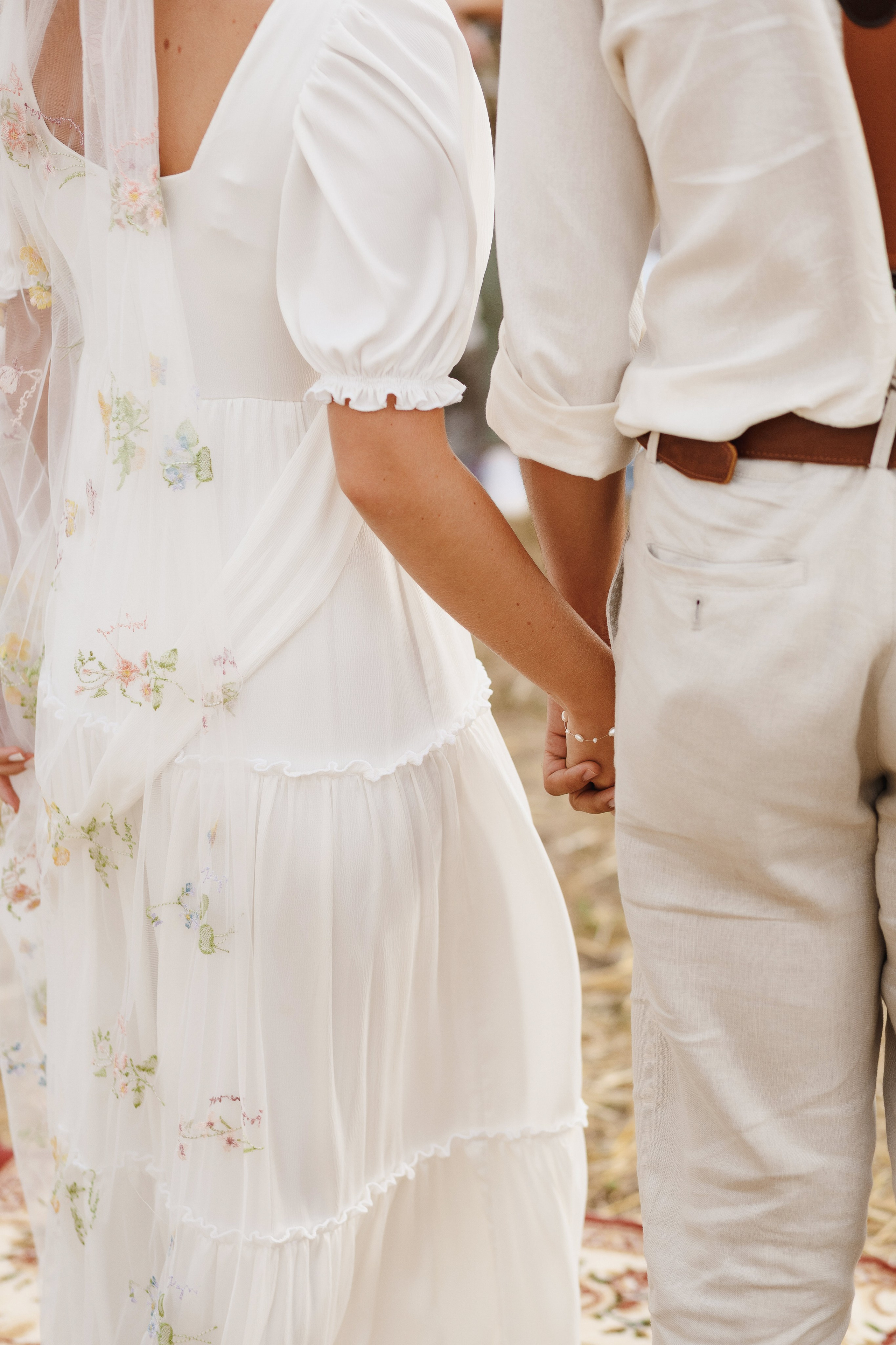 Деталь свадебного образа невесты и жениха: пара держится за руки во время церемонии — фотограф Таганрог