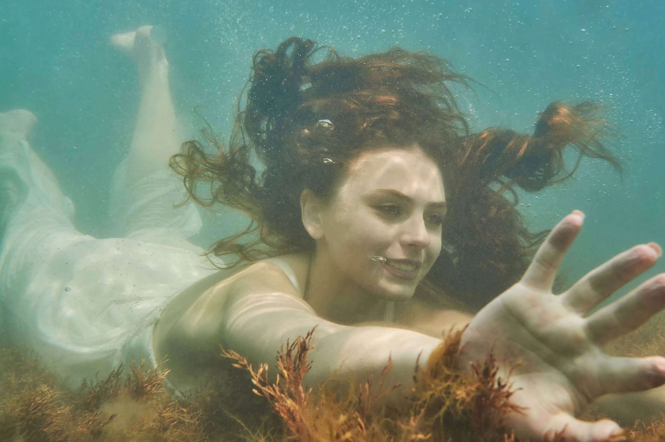 Девушка в белом платье плывет под водой