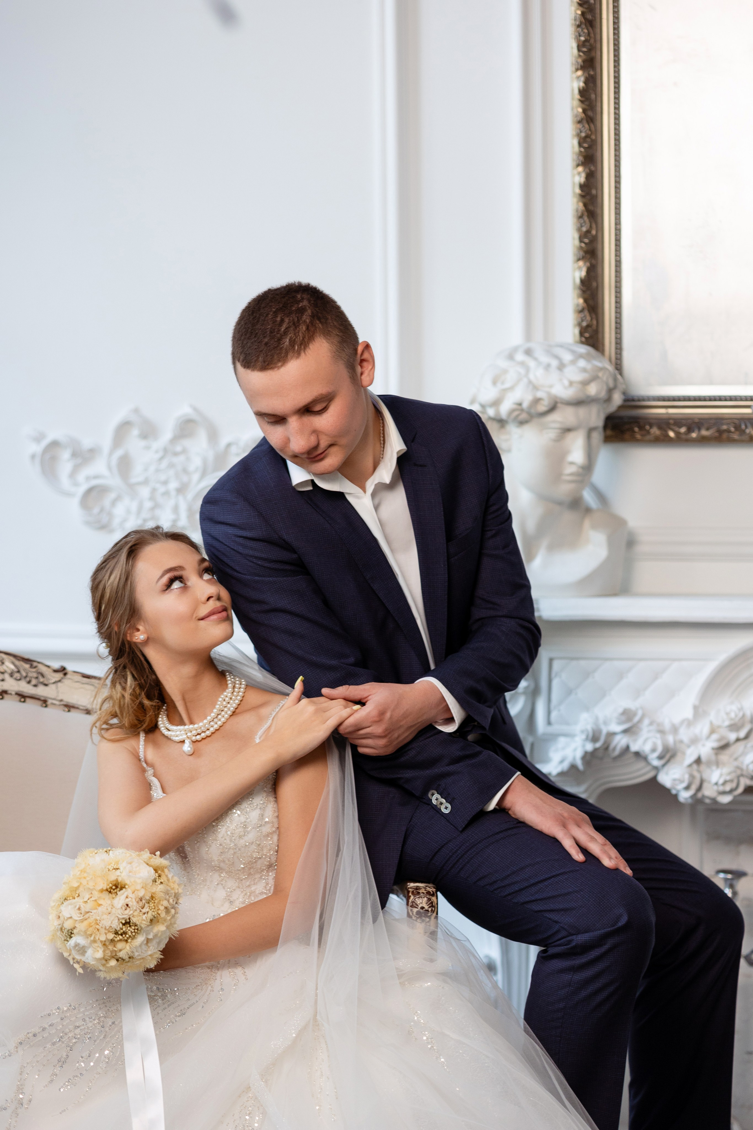 Невеста с женихом сидят на диване рука в руке