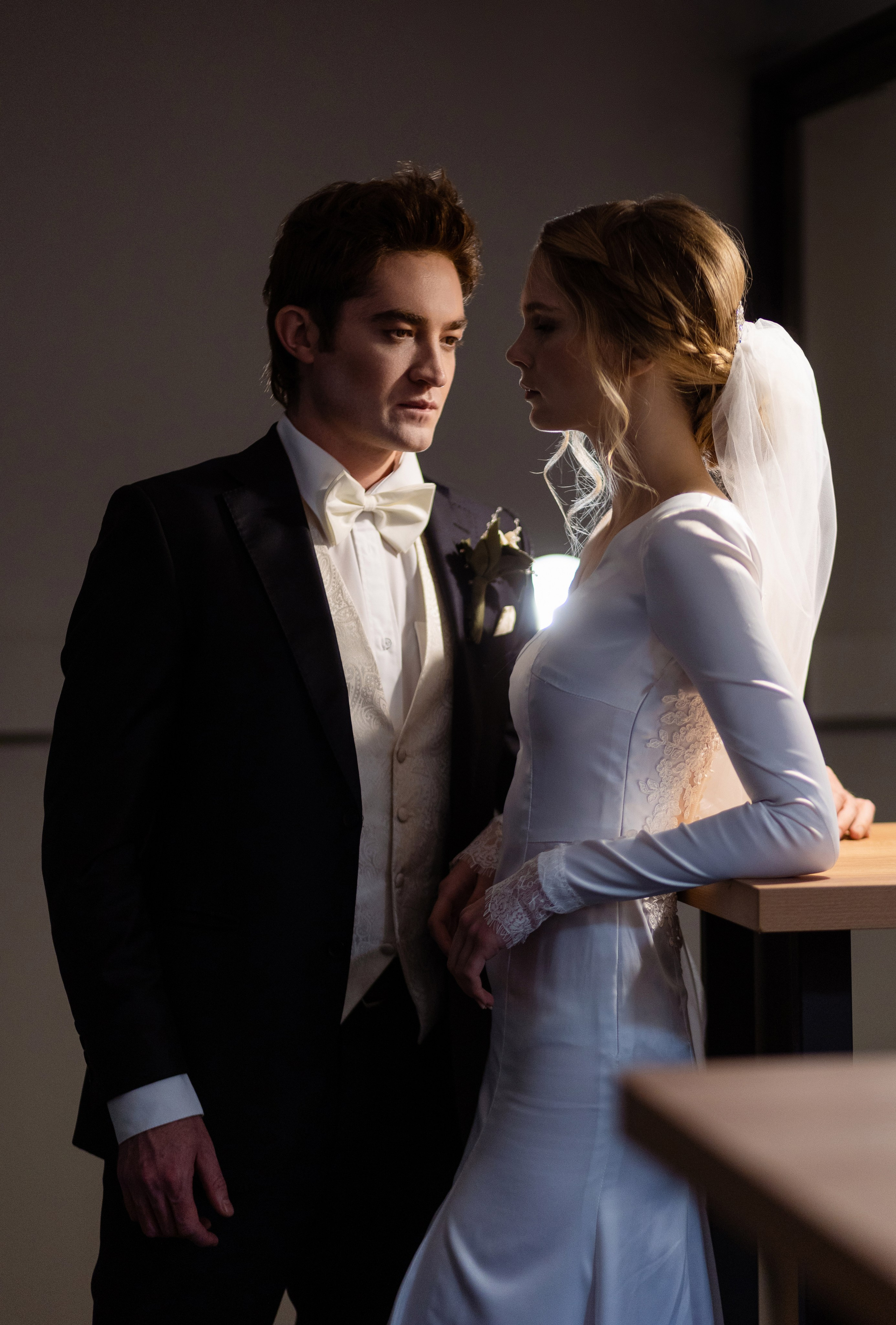 Невеста облокотилась на стол, смотрит на жениха.