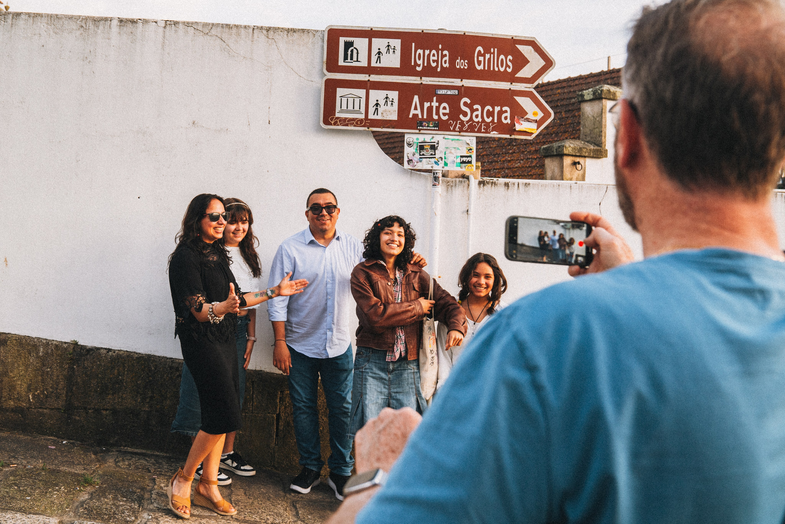 Группа людей семья влюбленные гуляет по живописной узкой улочке в Португалии, окружённой старыми домами и зеленью.