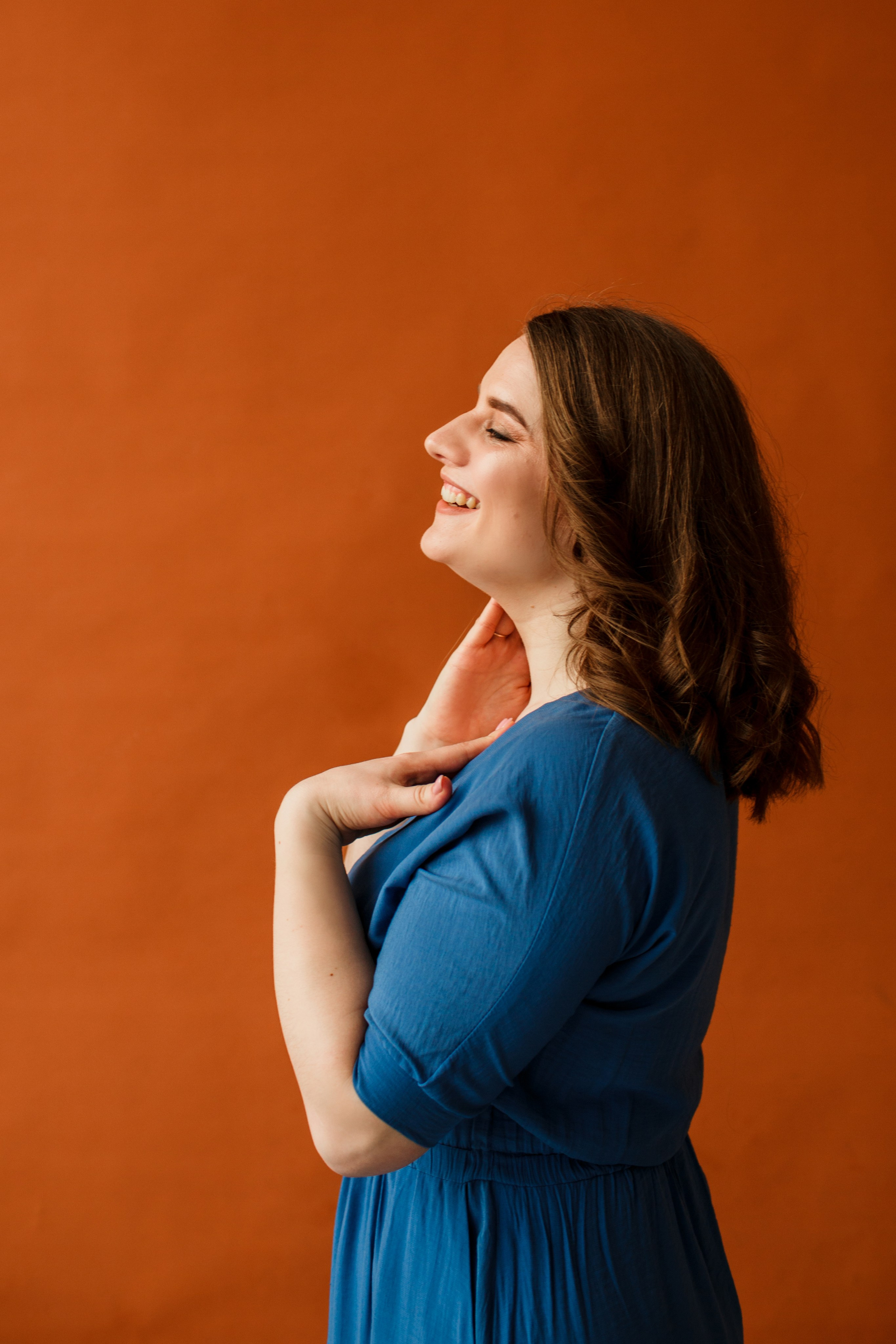 Модель прикасается к своей шее на бумажном коричневом фоне.