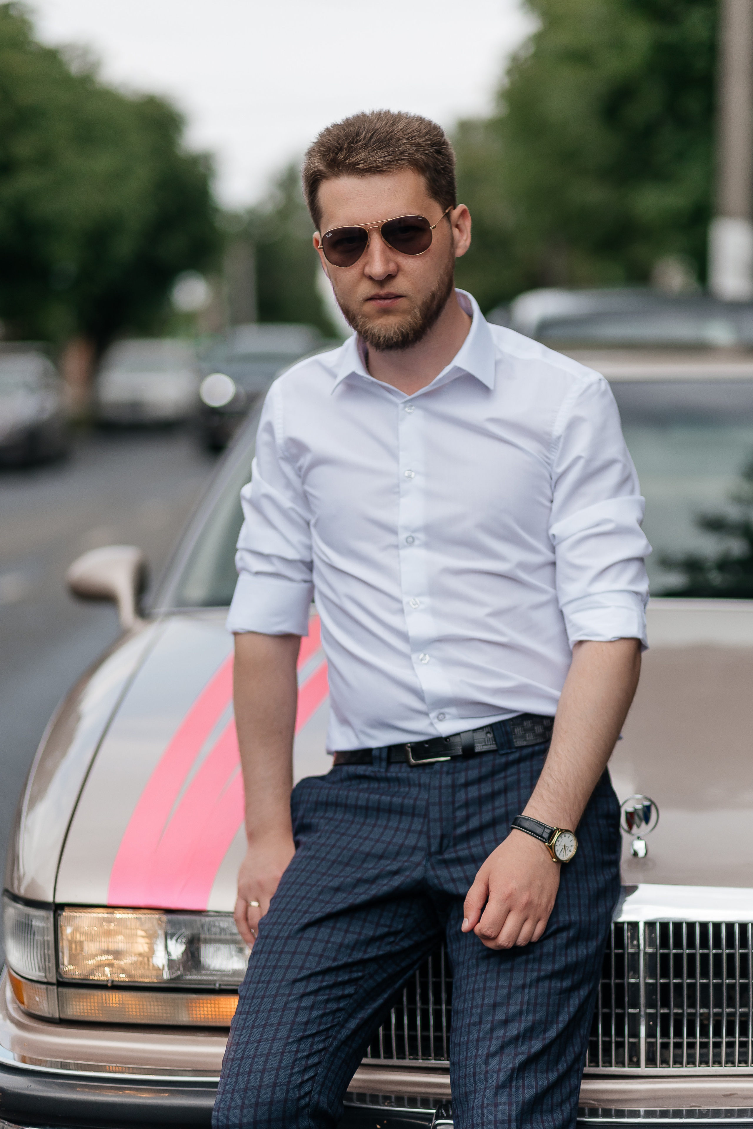 Мужчина сидит на капоте свадебного автомобиля