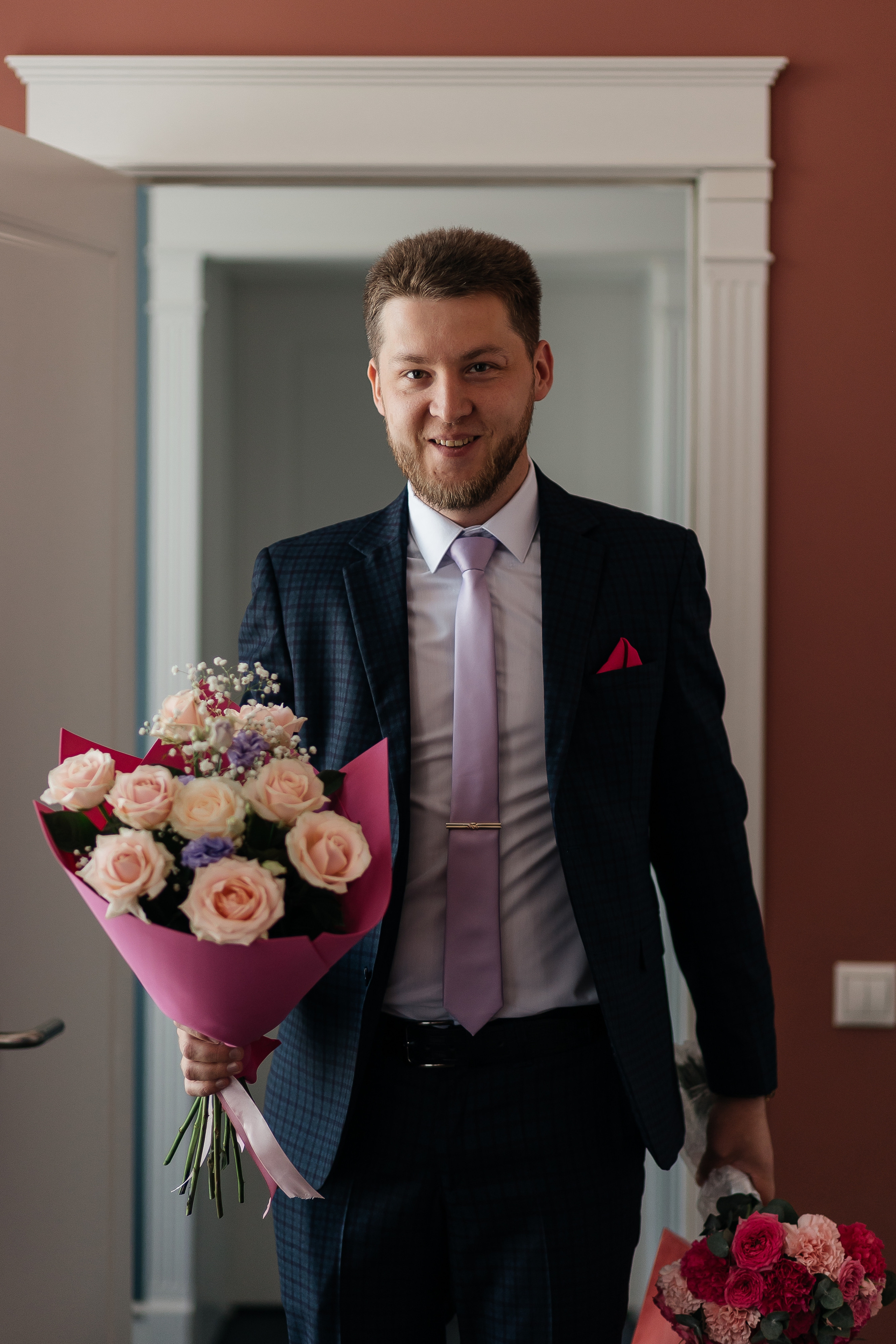 Мужчина входит в номер отеля с букетом цветов
