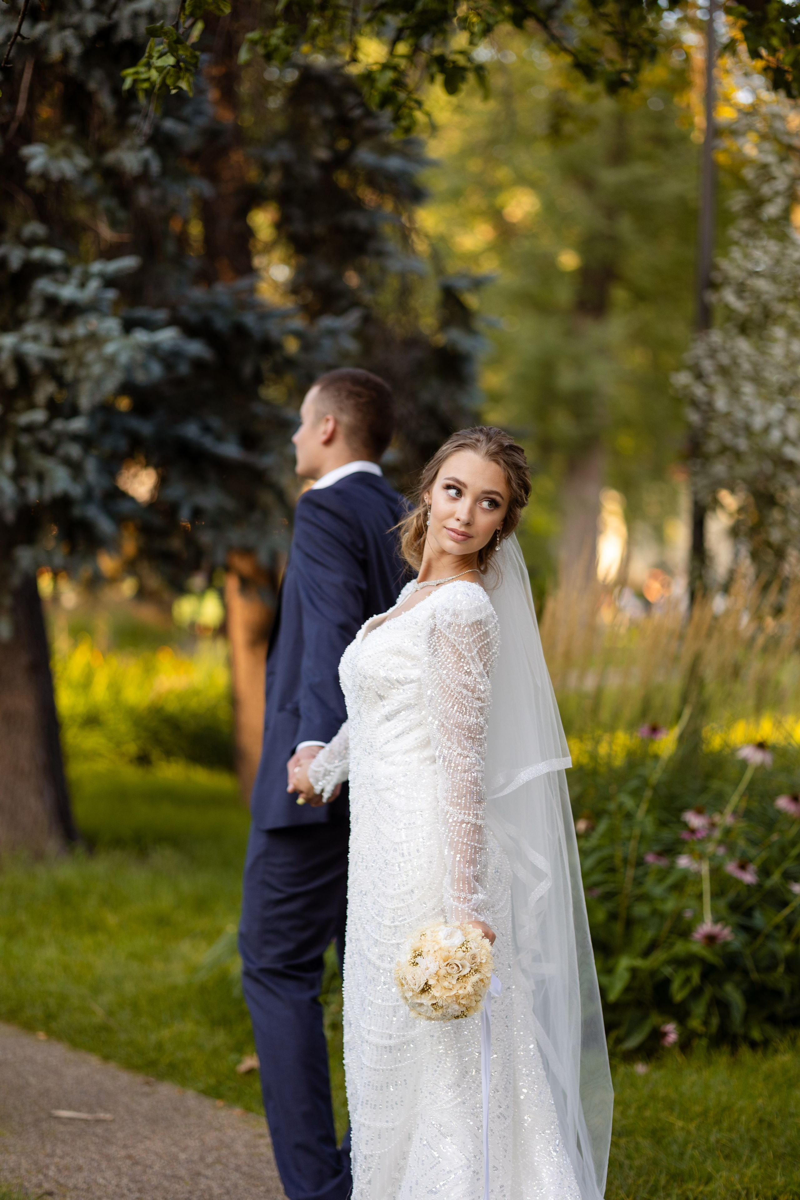 Жених ведет невесту в зеленый парк.