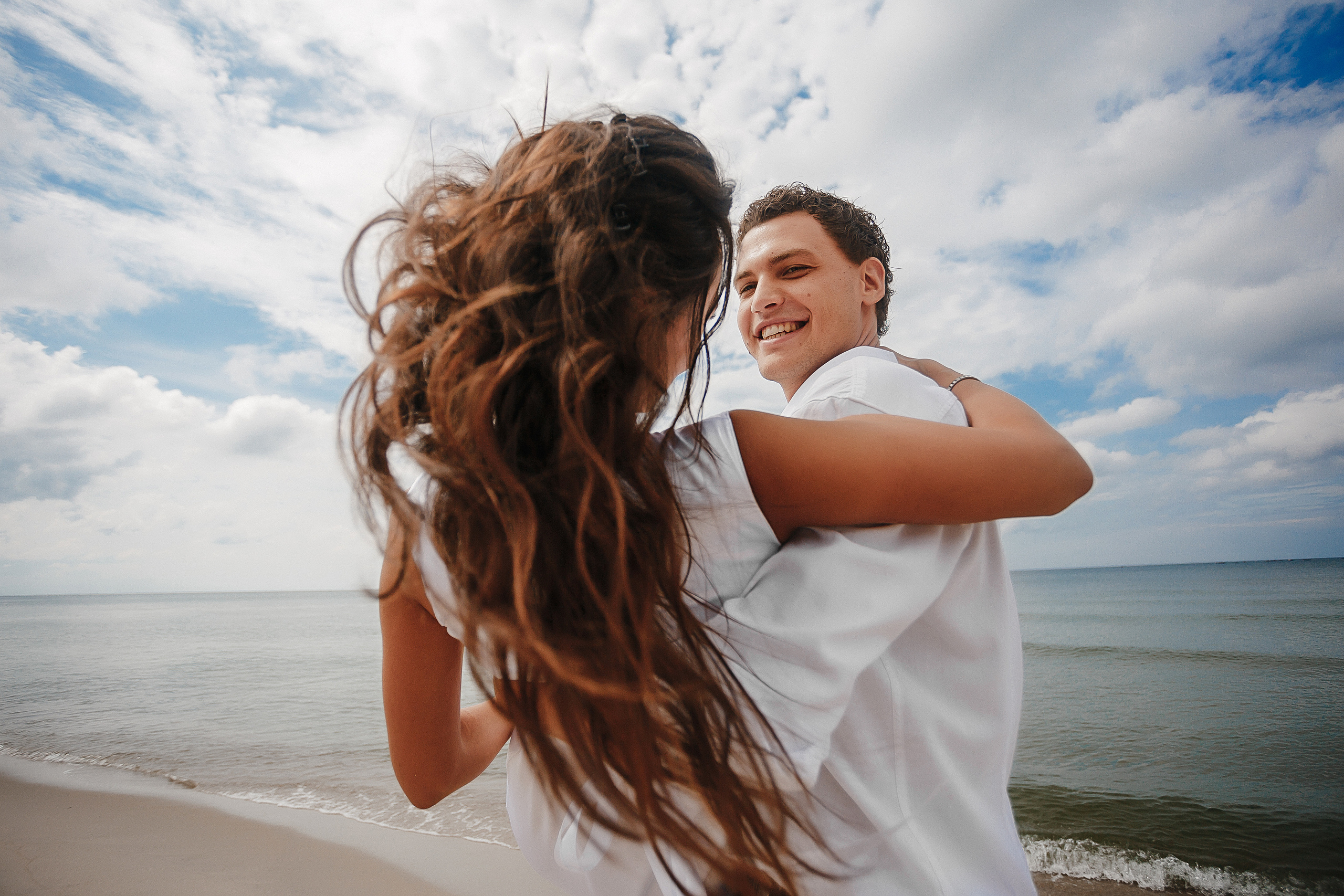 Жених держит невесту на руках на берегу Балтийского моря летом