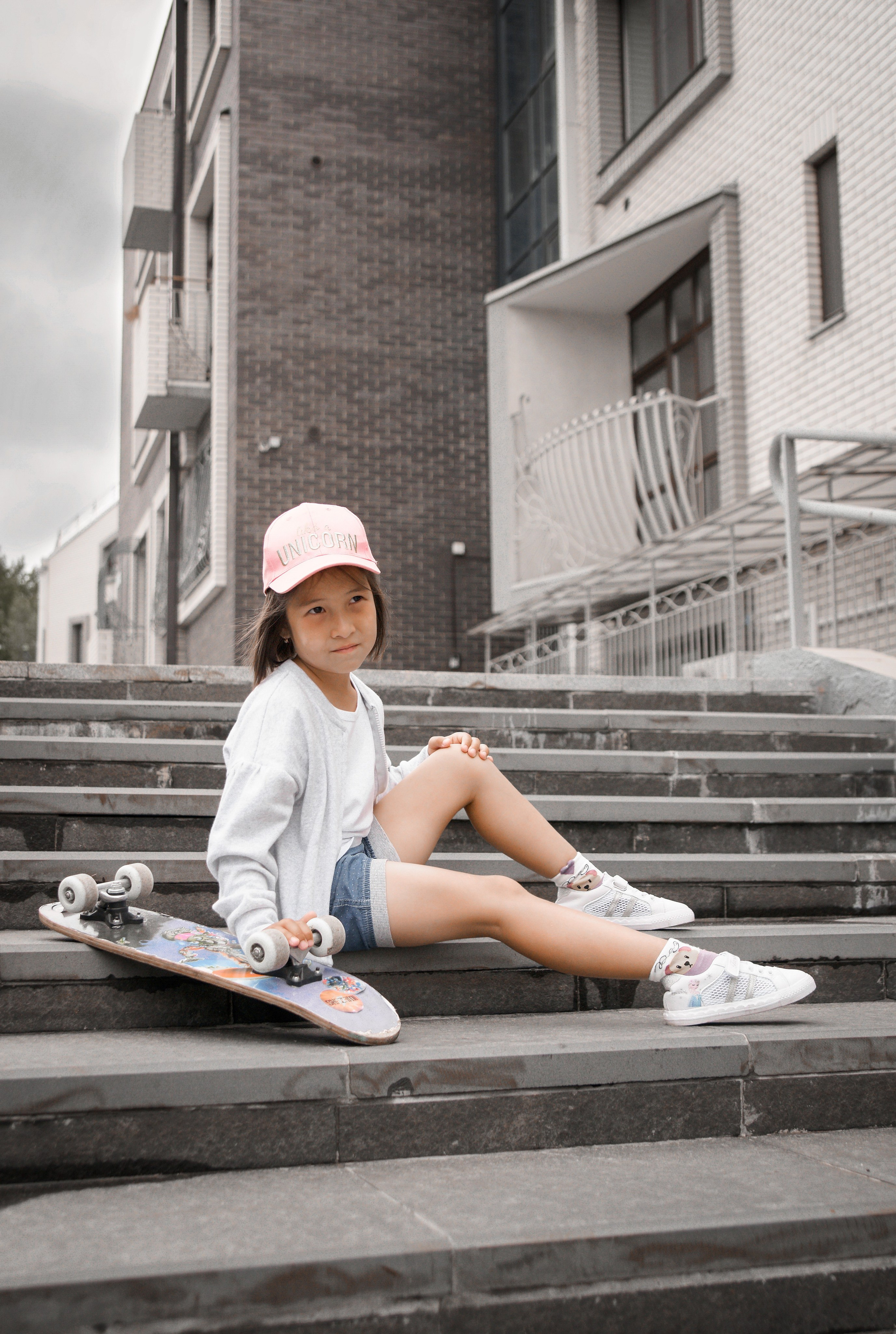 Детская фотосессия летом - девочка сидя в бейсболке на лестнице