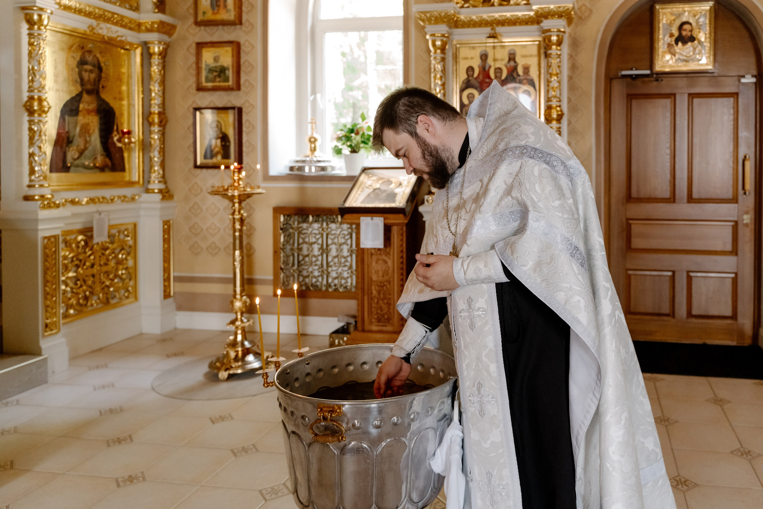 Священник совершает обряд крещения ребенка в православном храме.
