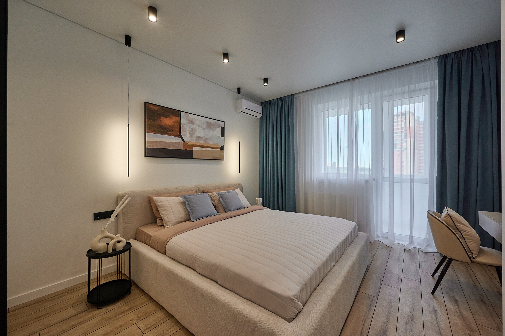 комната светлые оттенки белая кровать черный столик у кровати белый стол с бежевым стулом голубые шторы белый большой шкаф