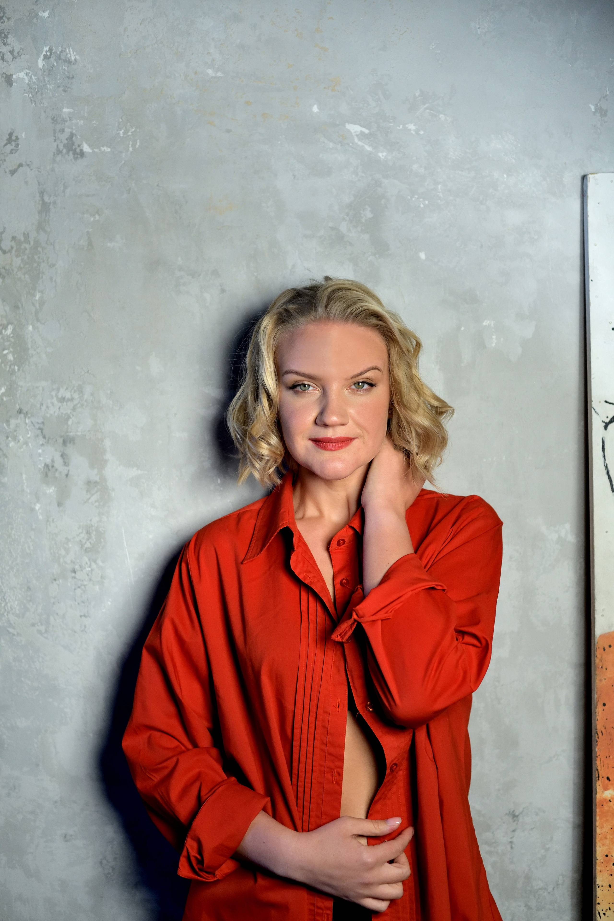 Девушка в красном на фоне серой стены в студии.