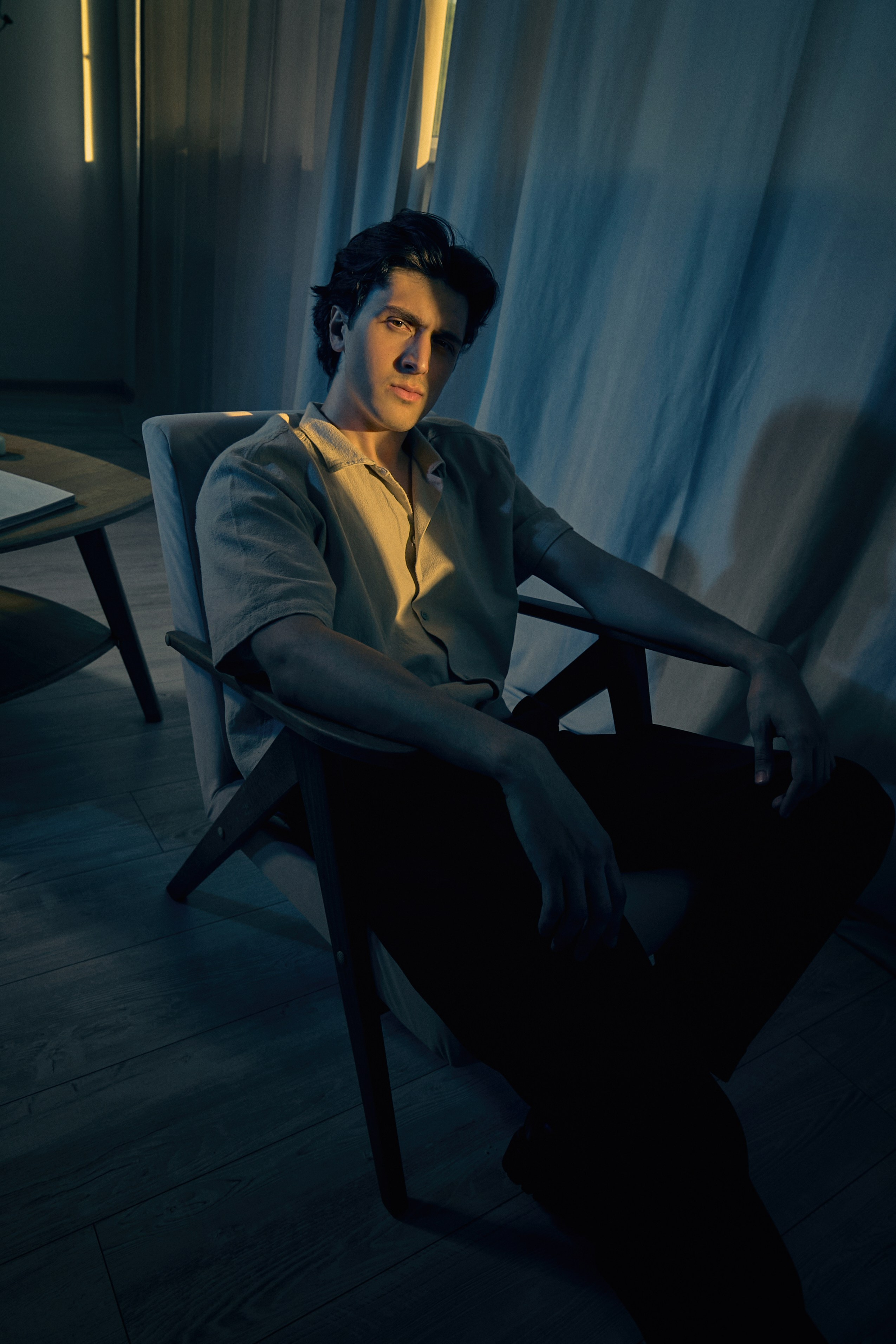 Жёлтый и синий свет, мужчина в кресле щурится