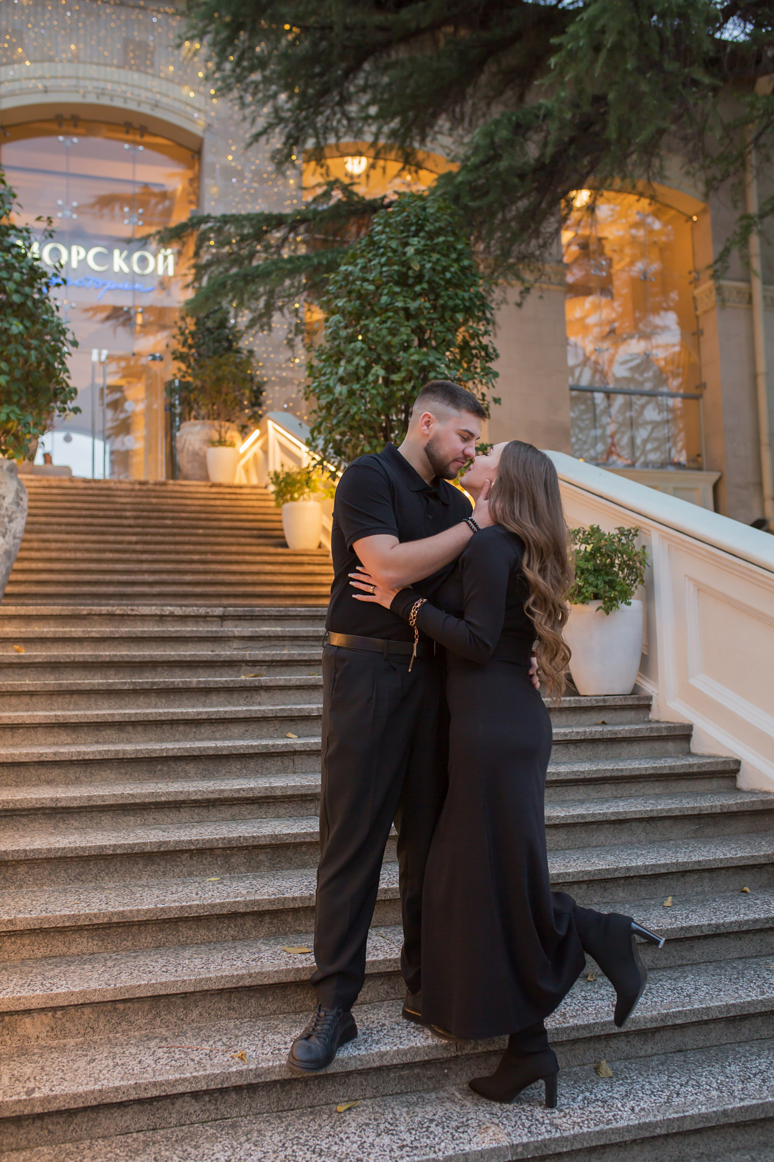 парень и девушка стоят на ступенях целуются
