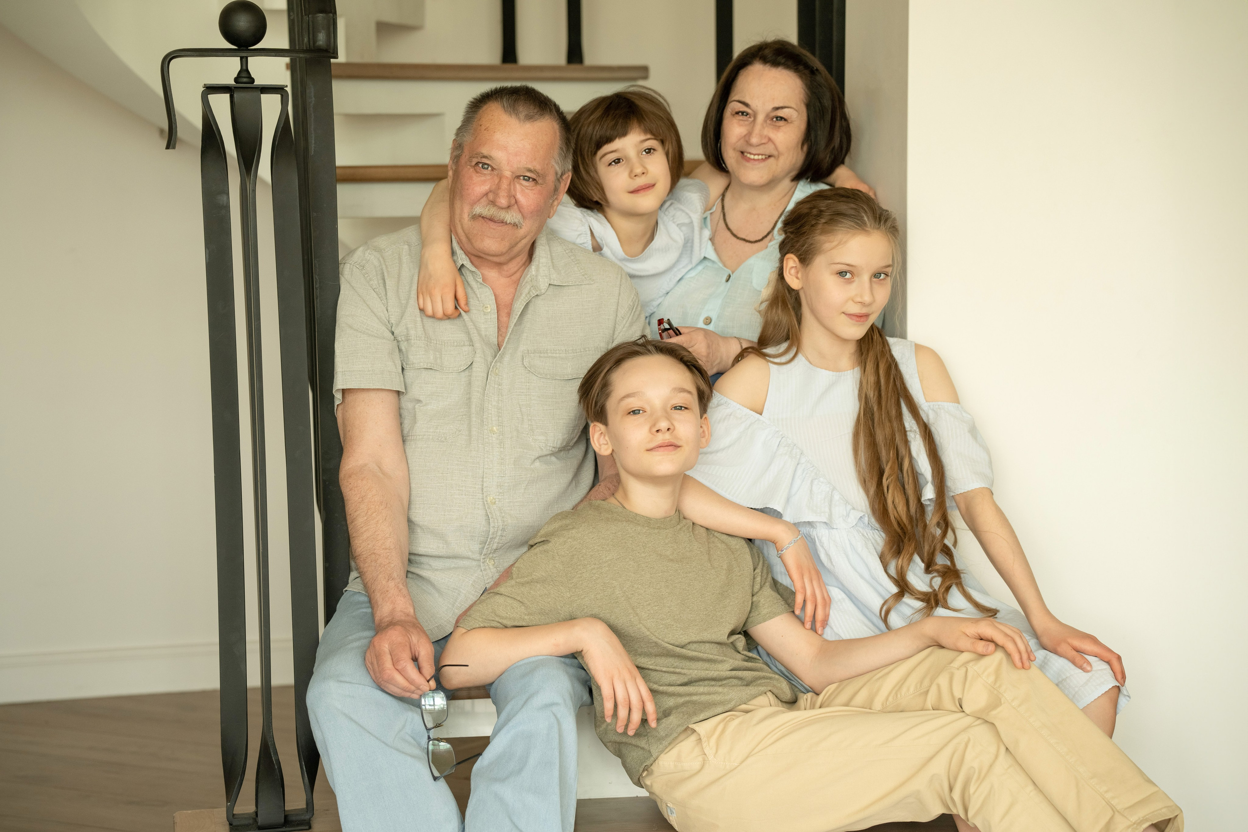 Фото внуков с дедушкой и бабушкой. Они сидят на лестнице в доме.