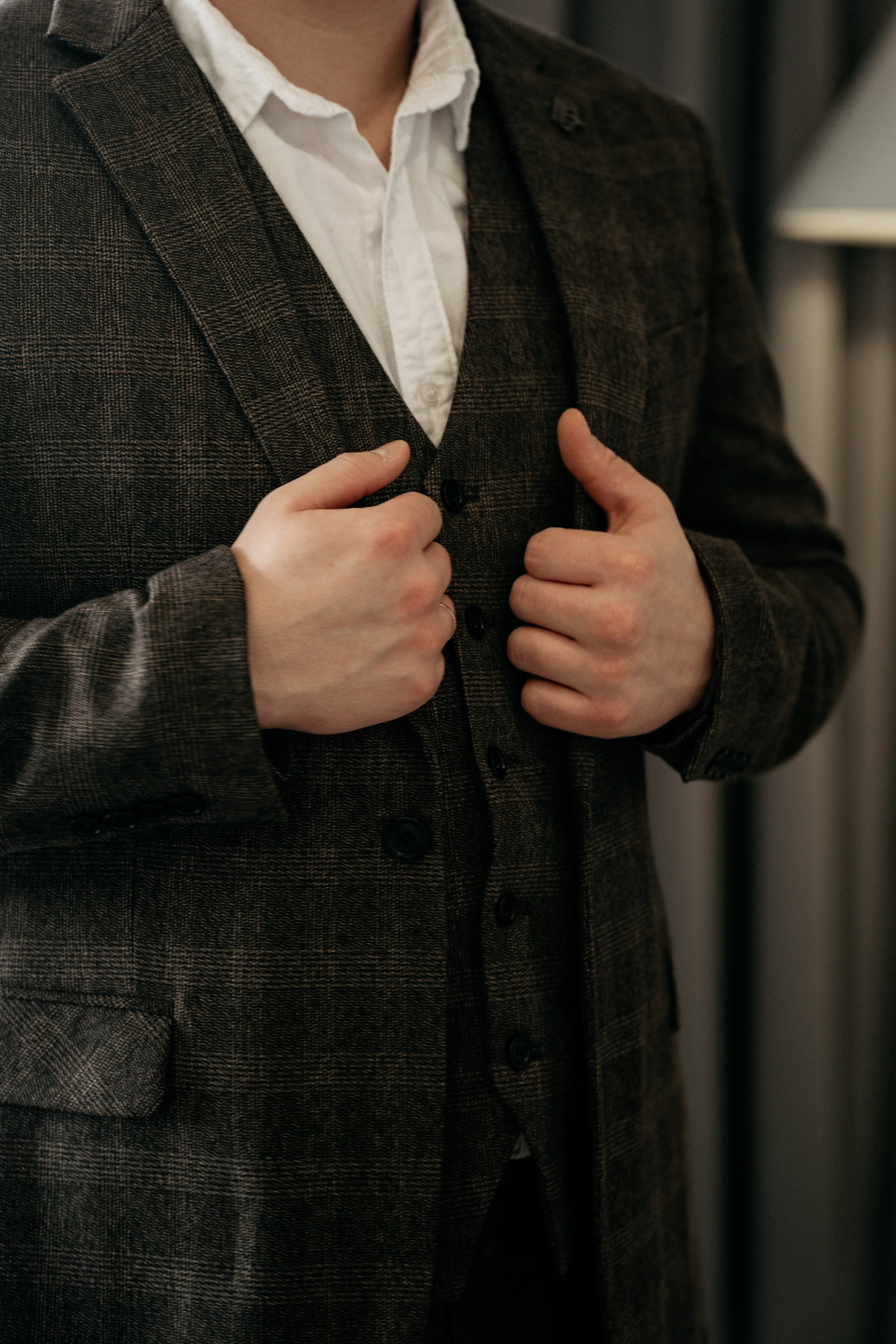 Деталь свадебной серии фотографии, жених одевает пиджак, сборы жениха и невесты в номере отеля