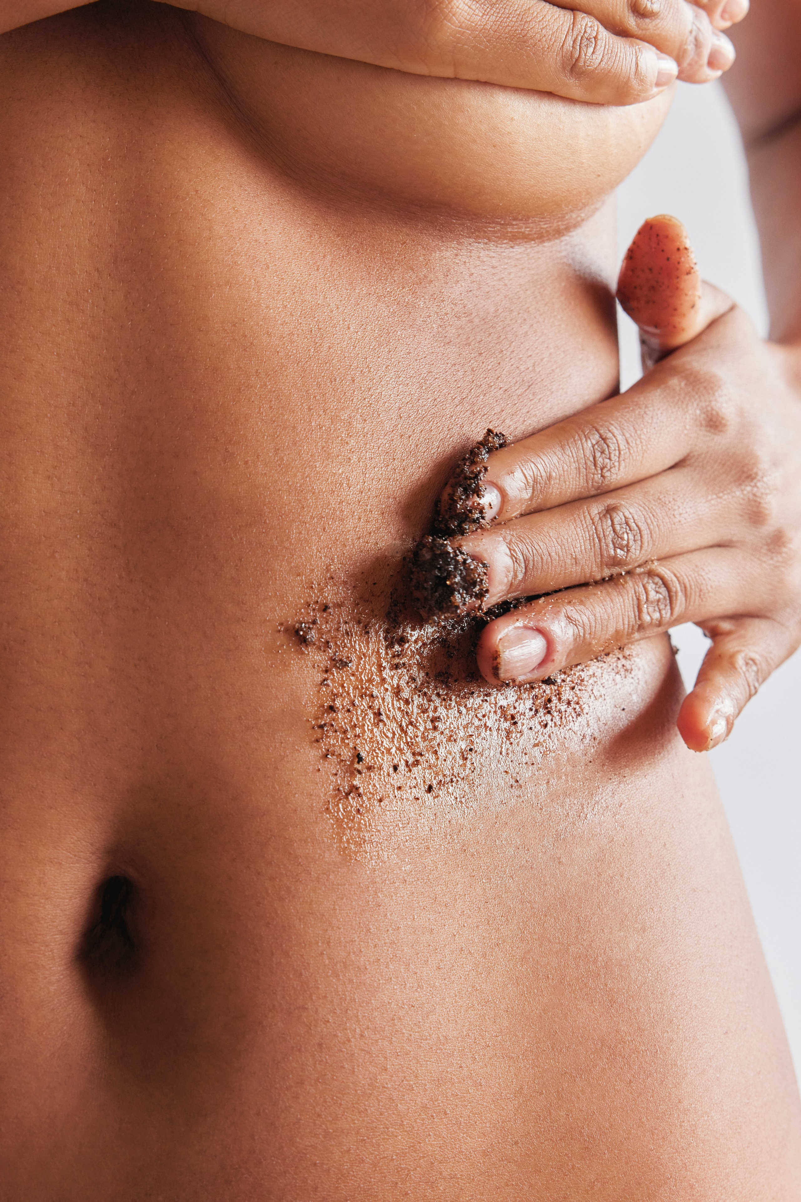 Application of coffee scrub on skin, emphasizing exfoliation benefits for glowing skin.