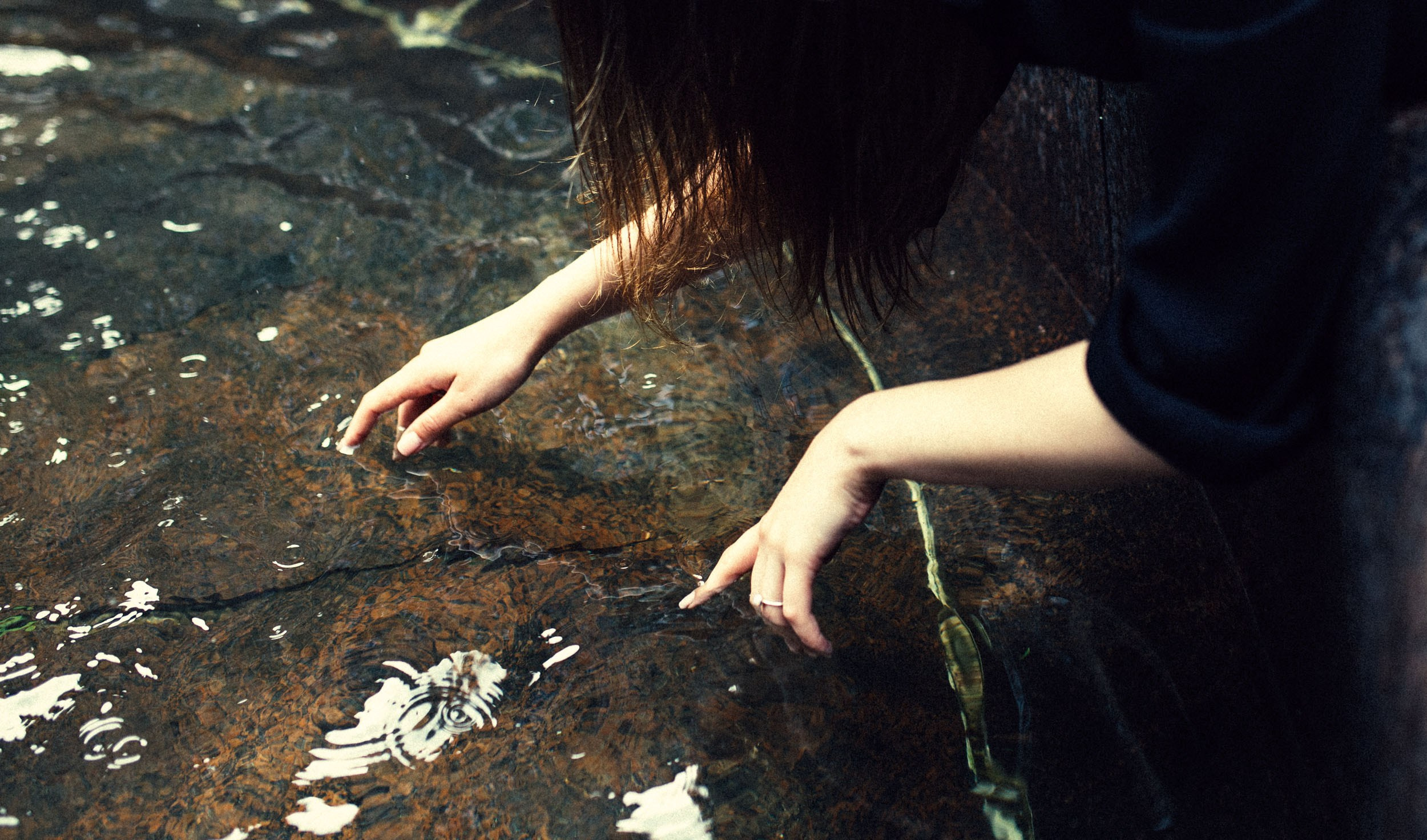 Девушка трогает воду в фонтане