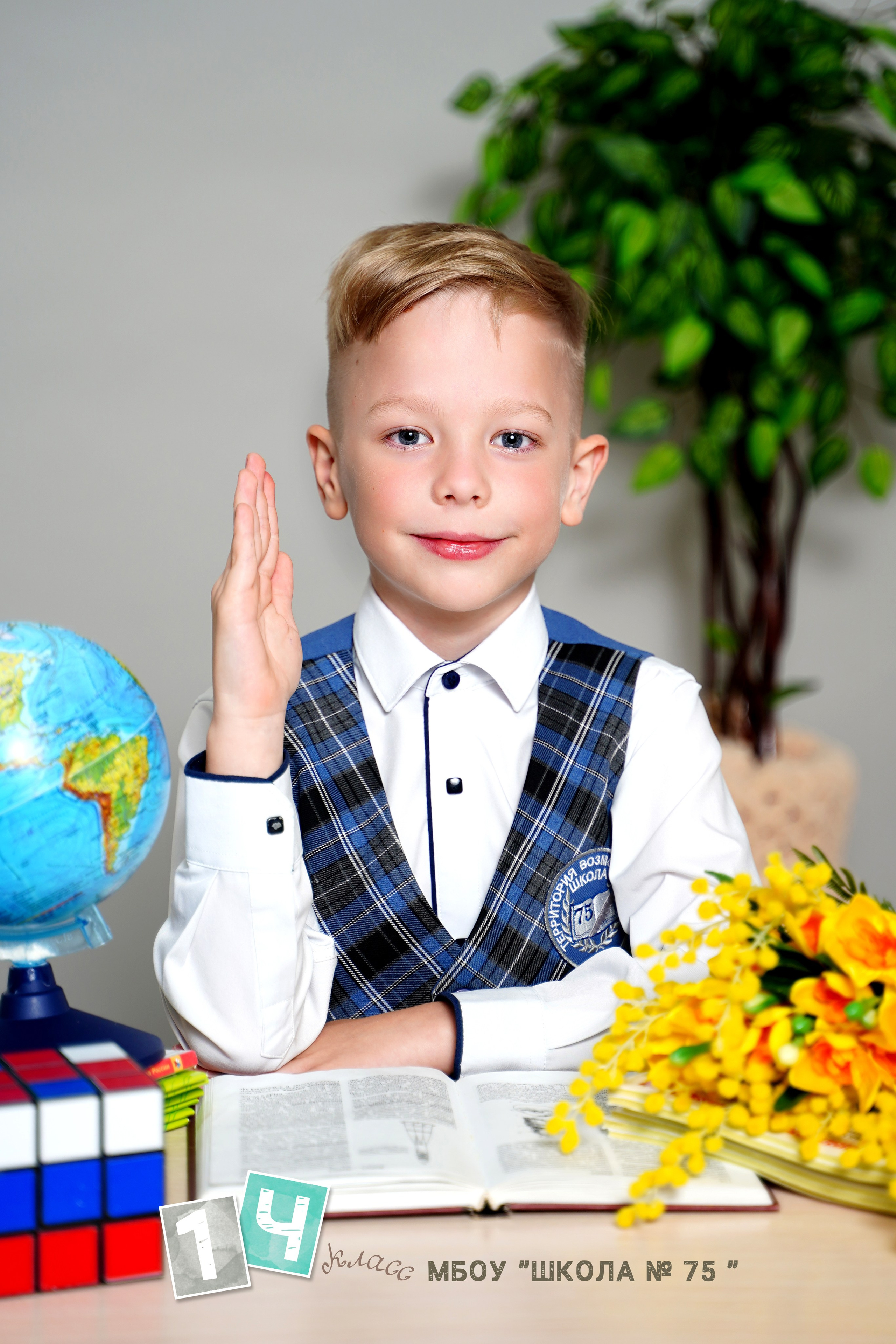 Фон серый, однотонный, портрет ребенка сидя за столом, предметы находятся на столе. 