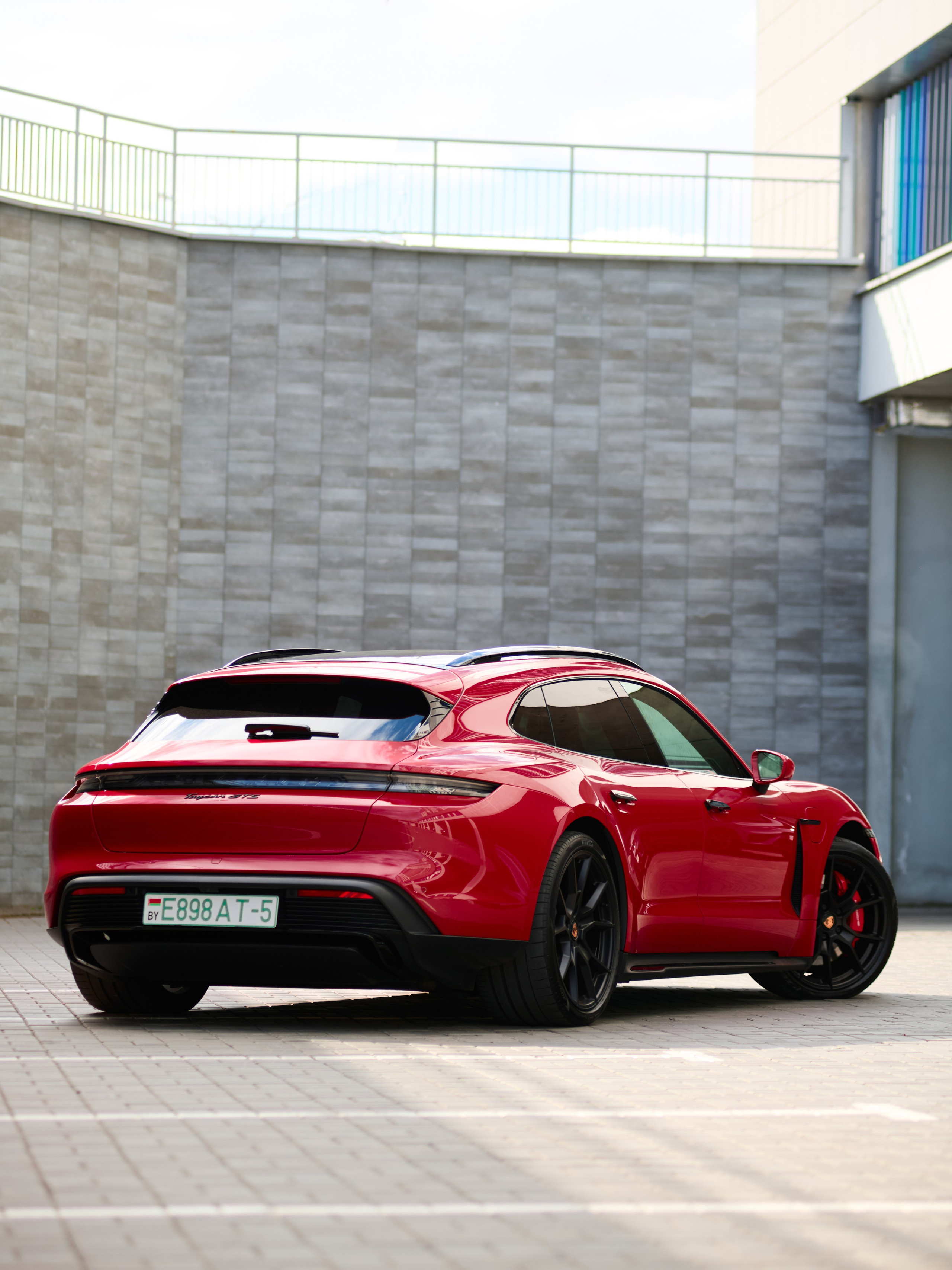 Красный Porsche Taycan GTS с заднего правого ракурса на парковке