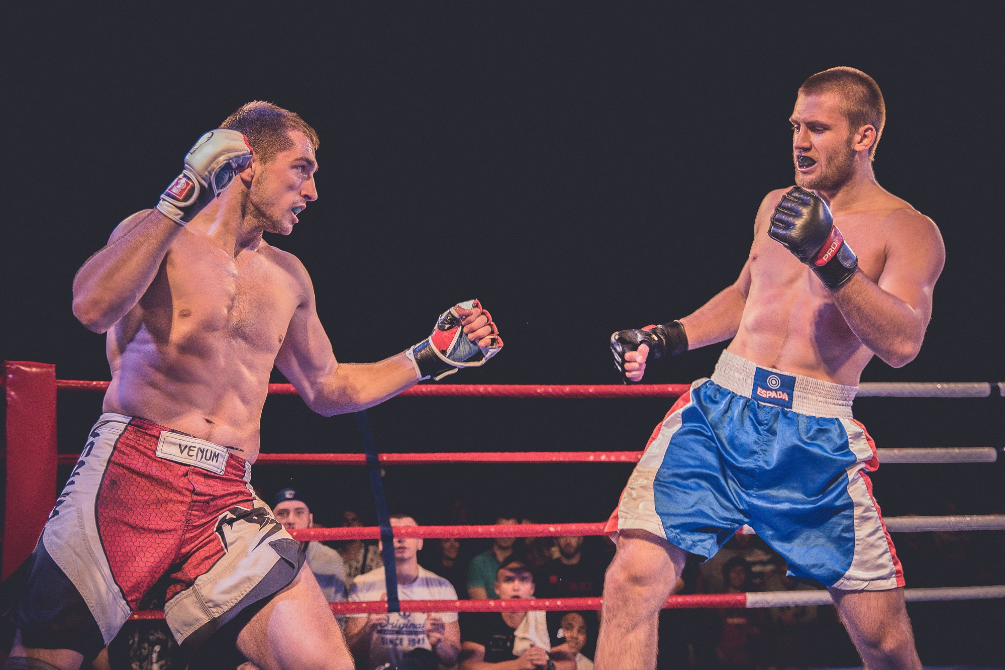 Боец в красных шортах пытается нанести удар сопернику