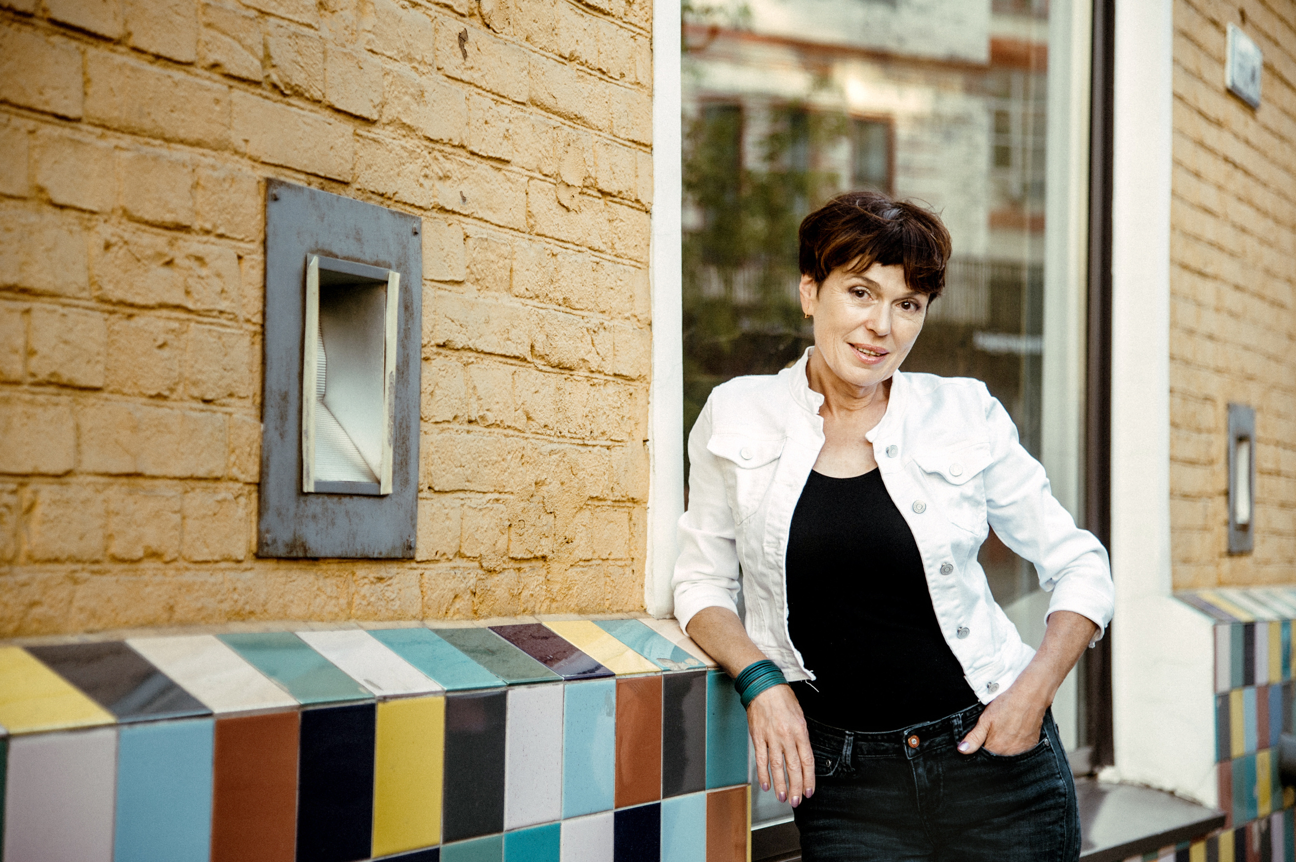 Летняя портретная фотосессия женщины в белой куртке в арт-пространстве