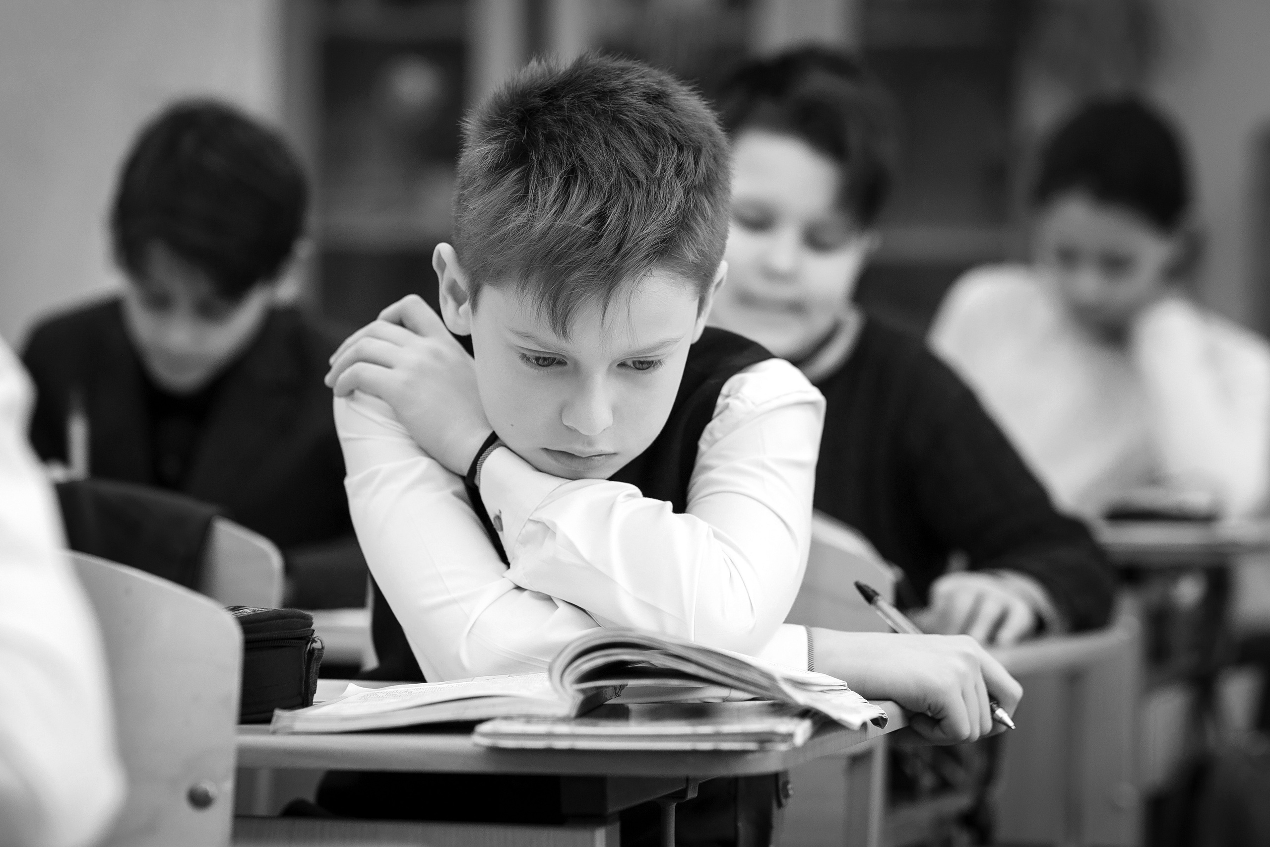 На уроке мальчик задумчиво смотрит в книгу 