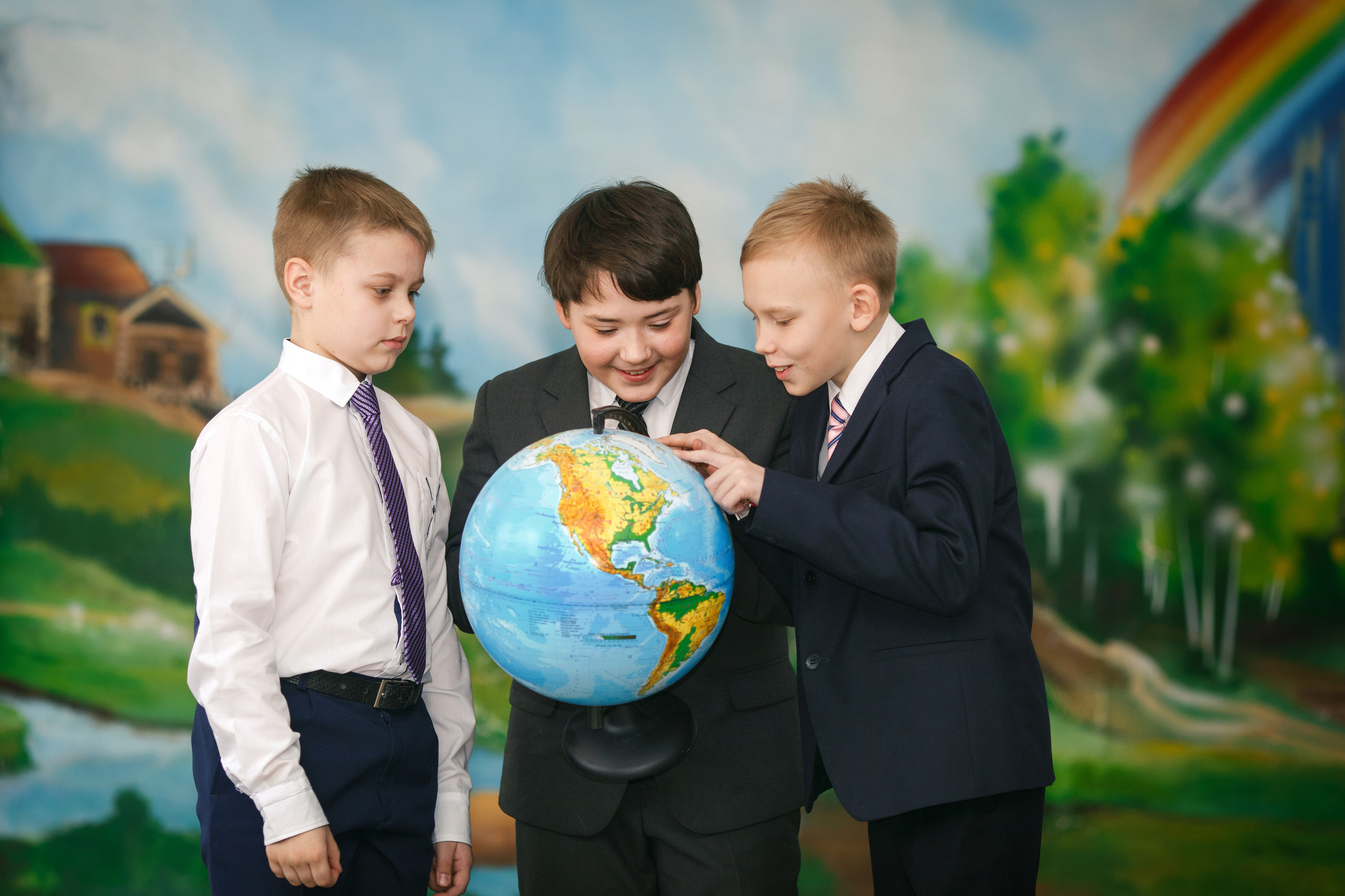 Три ученика младших классов рассматривают глобус