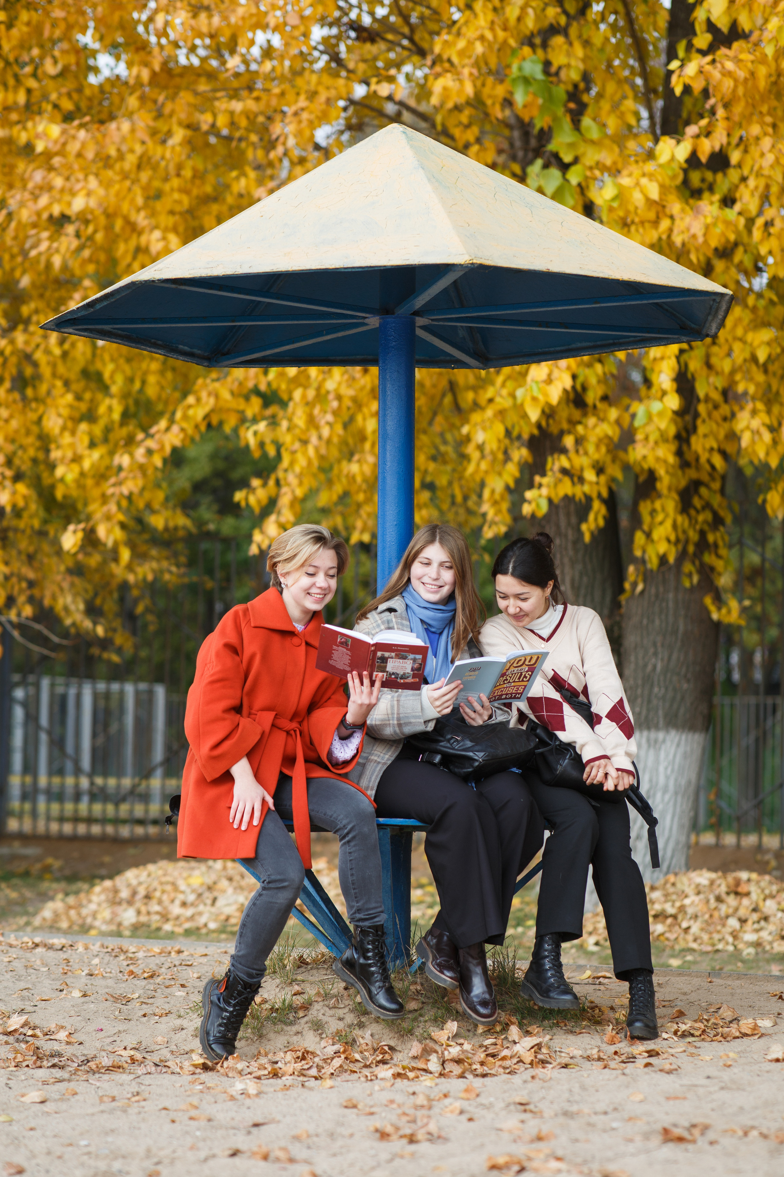 Девочки на набережной на осеннем пляже читают книгу