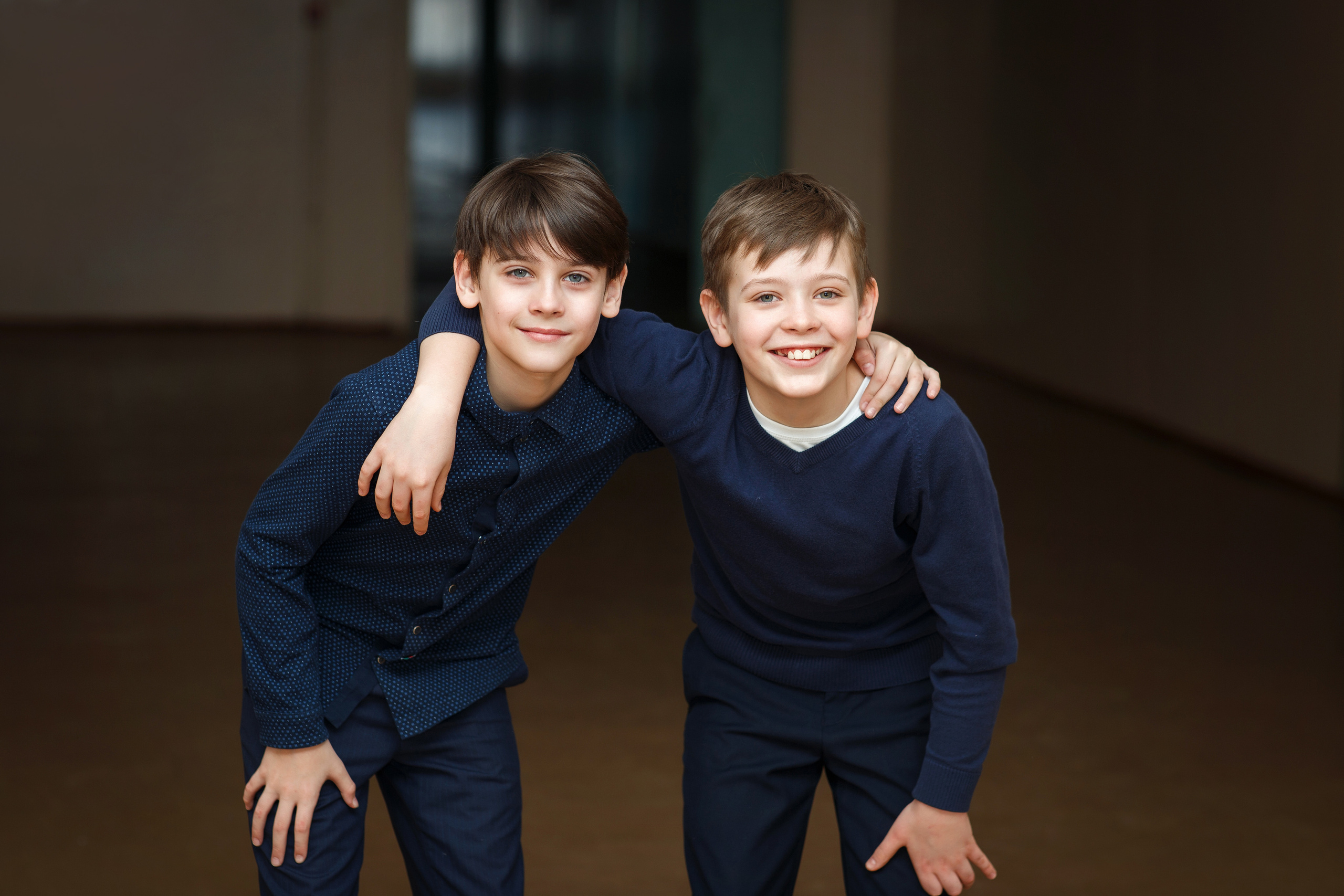 Два школьника-друга в коридоре школы стоят обнявшись и улыбаясь