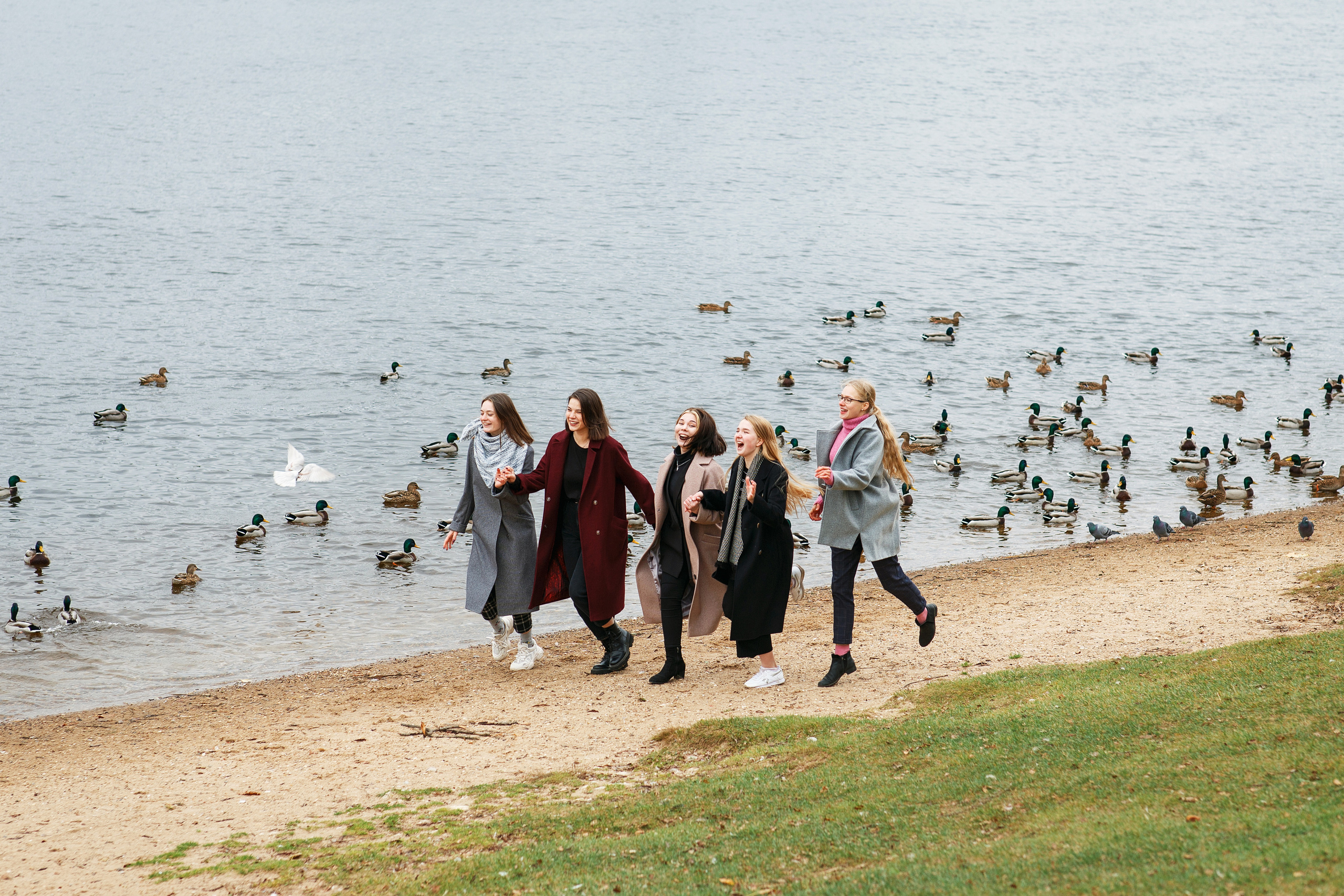 Несколько девочек бегут по берегу реки