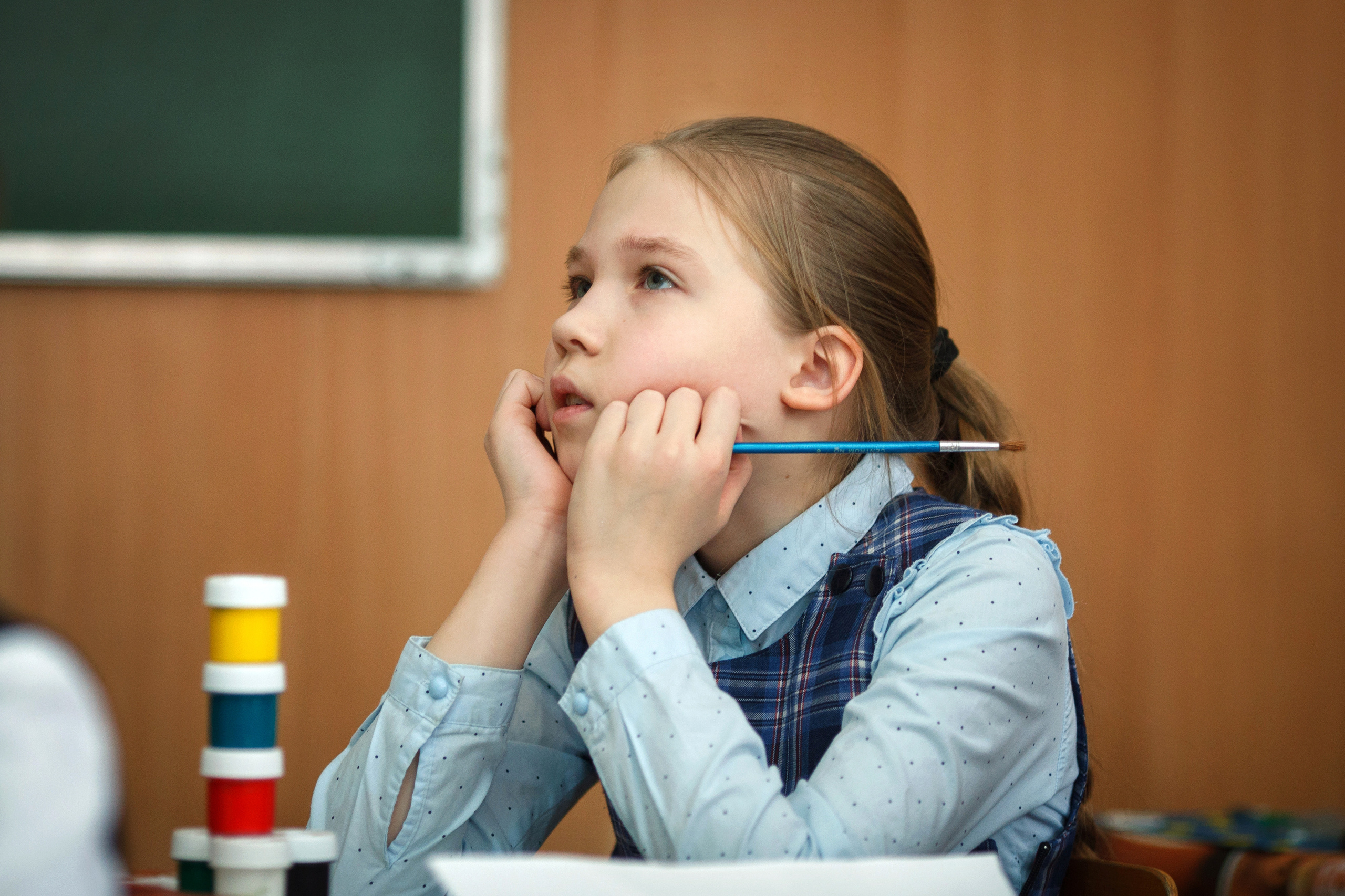 Девочка сидит за партой на уроке и смотрит на доску